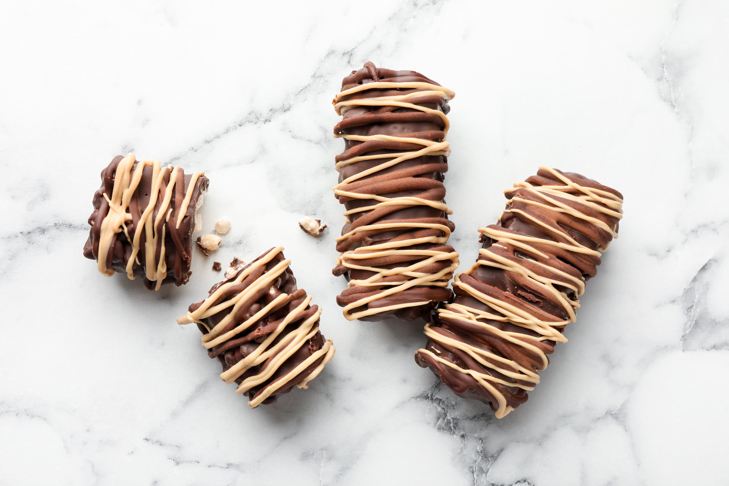 Delicious chocolate puffed rice bars on white marble table, flat lay