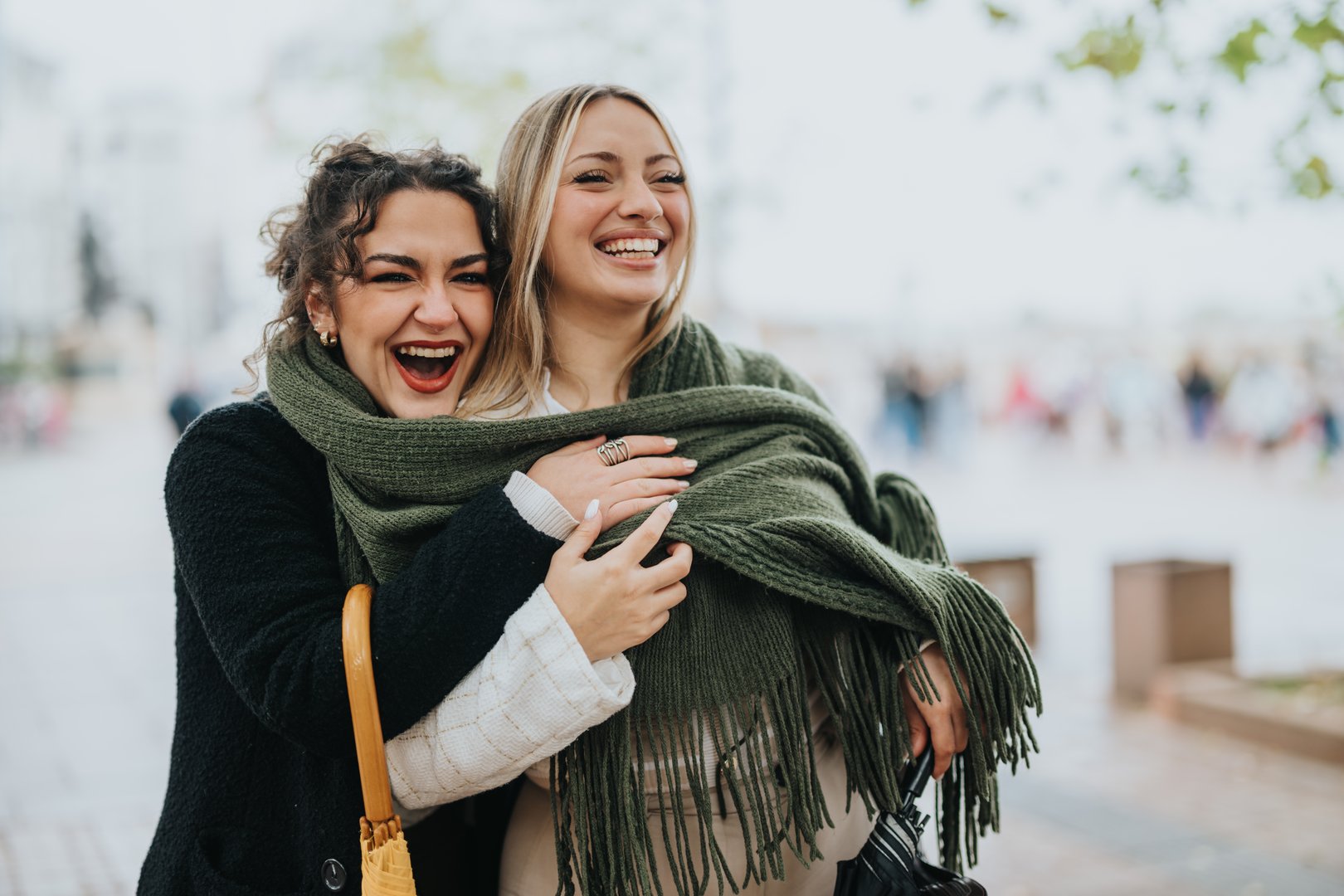 Two happy friends, warmly dressed, embrace and enjoy a cheerful outing in the city