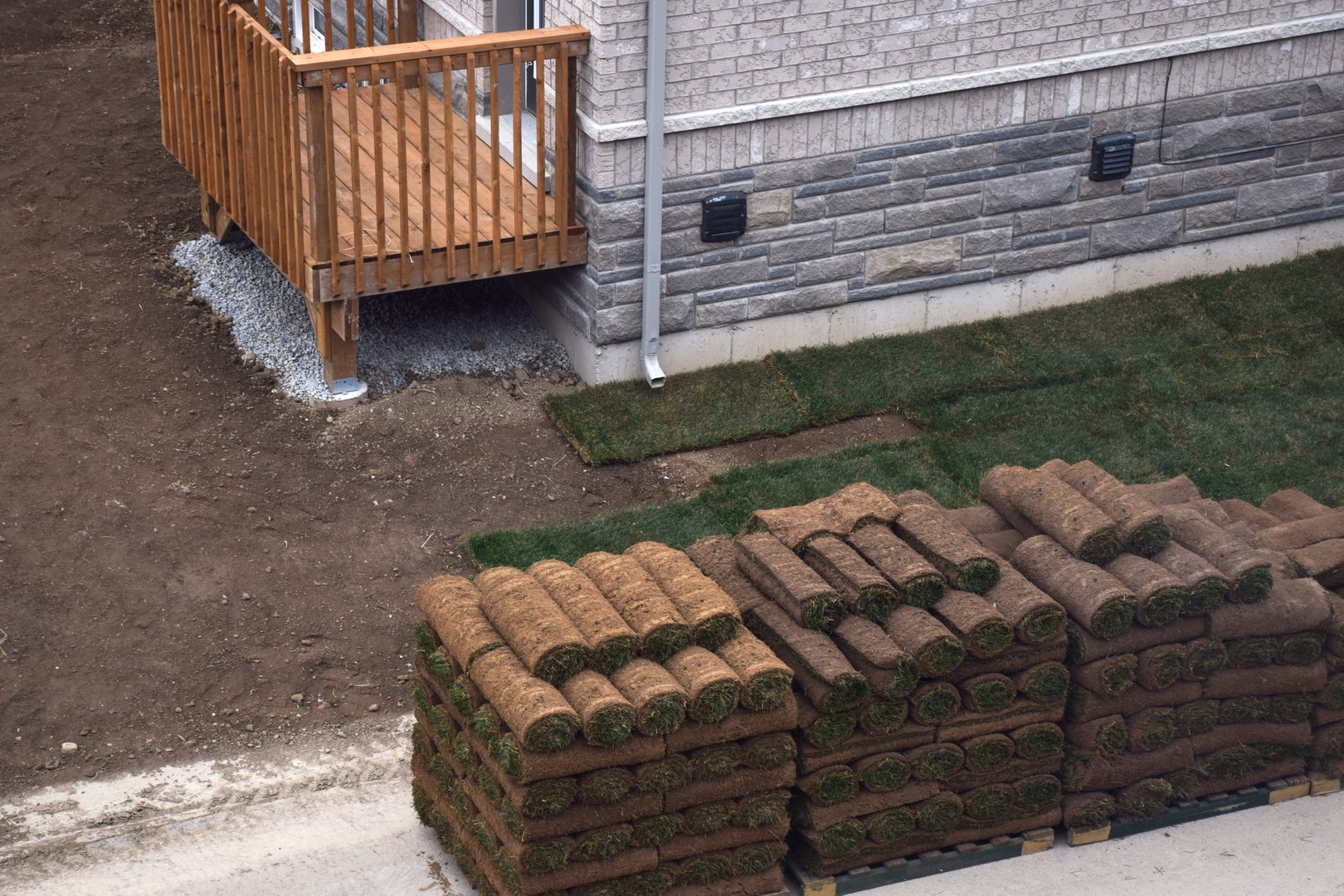 Fresh sod pallets waiting to be laid around residential home