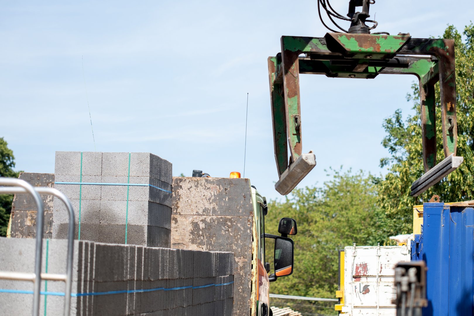 Delivery lorry HIAB with mobile crane and Brick Block Grab Lifting Attachment unloading and moving materials on construction site
