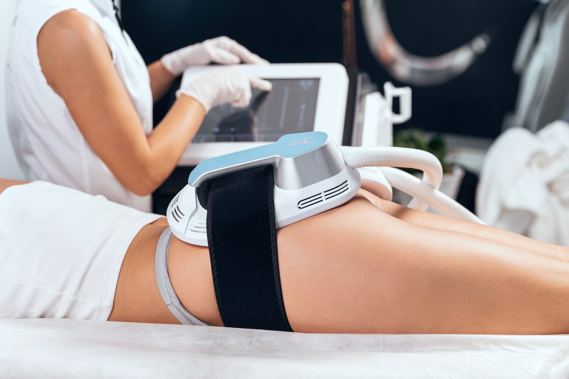 Close-up of woman lying receiving epilation laser treatment and anticellulite massage on buttock on the spa center.