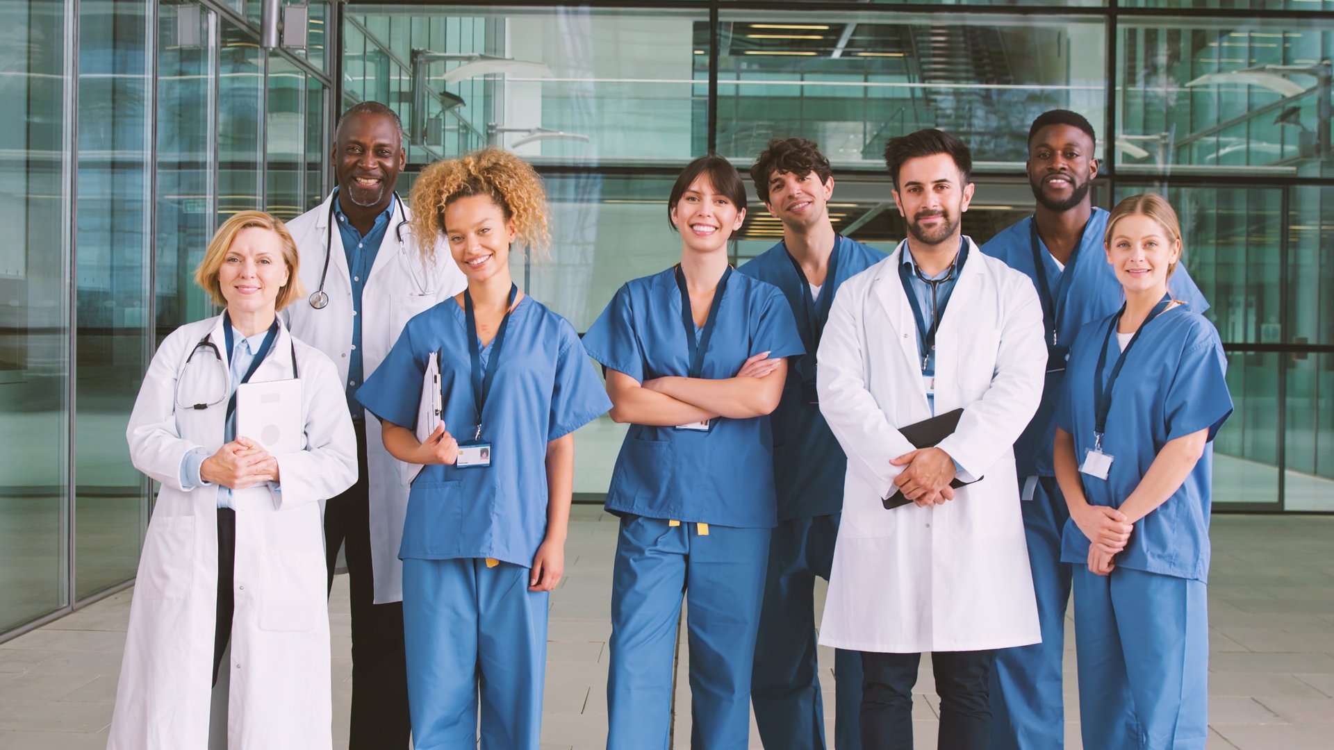 Portrait Of Smiling Medical Team Standing In Modern Hospital Building