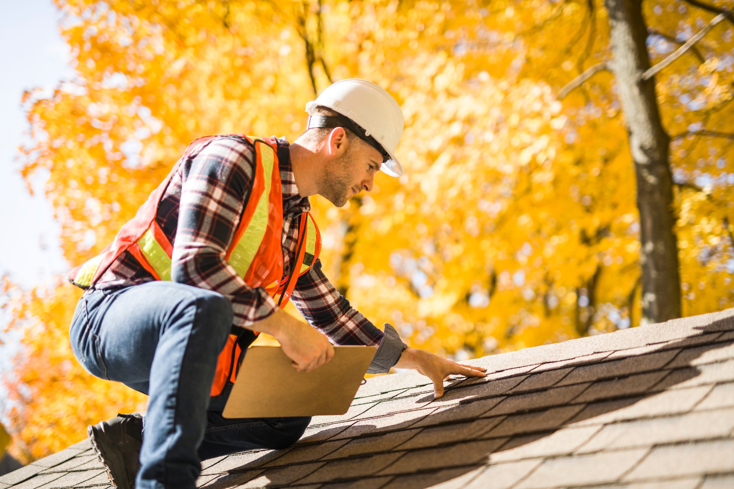 Man with hard hat inspecting house roof