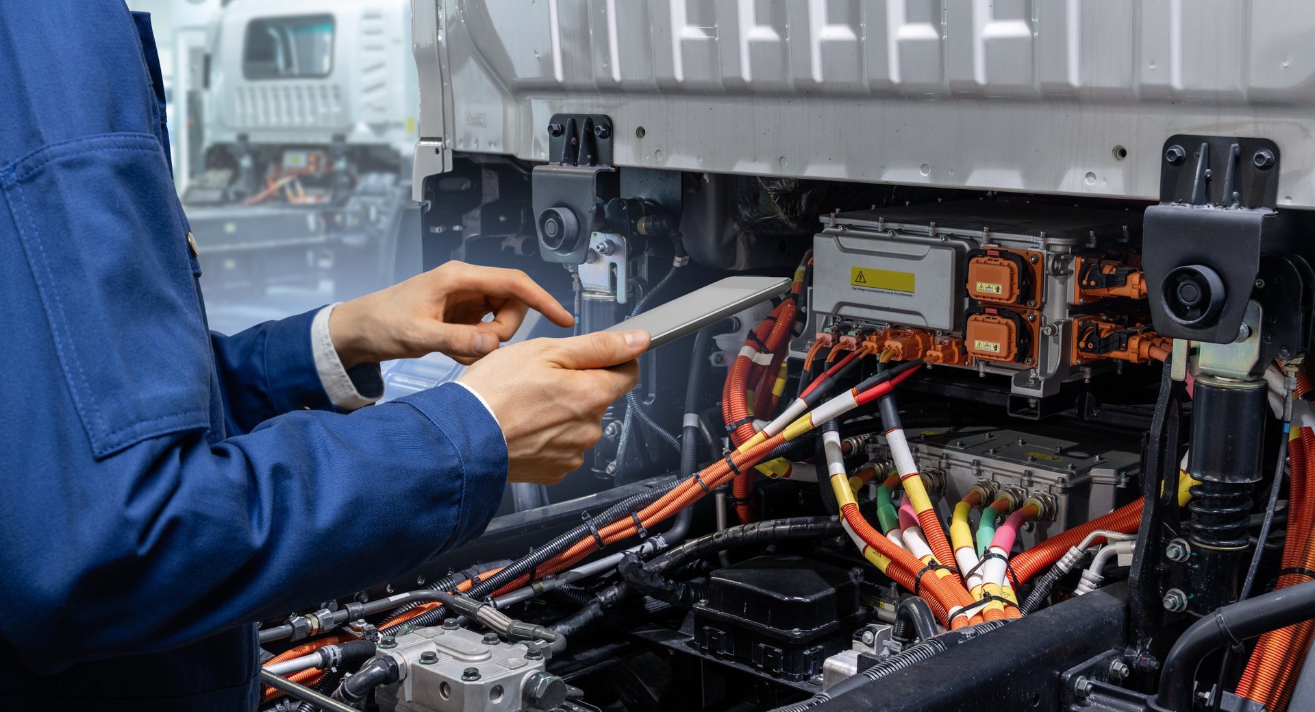 Serviceman with digital tablet next to electric truck. Electric vehicles maintenance.