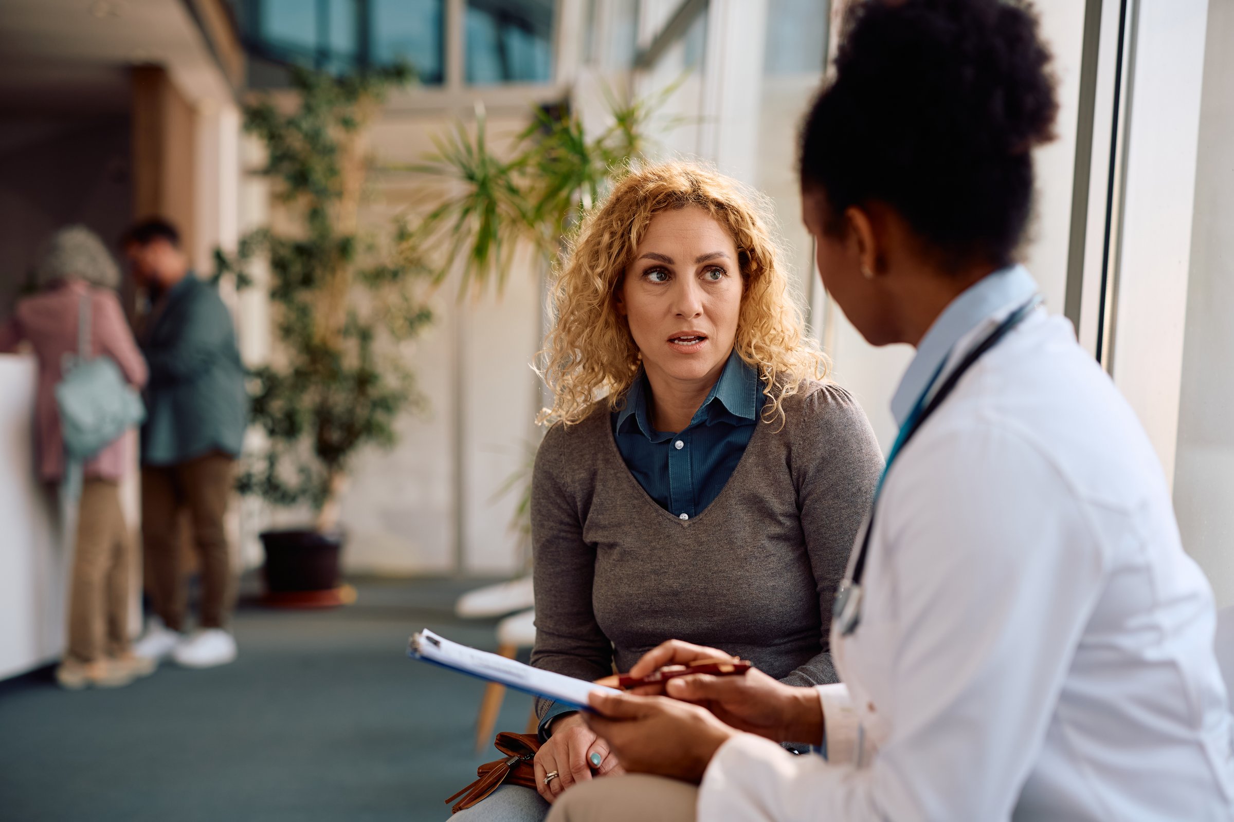 Distraught woman communicating with African American female doctor at the clinic.