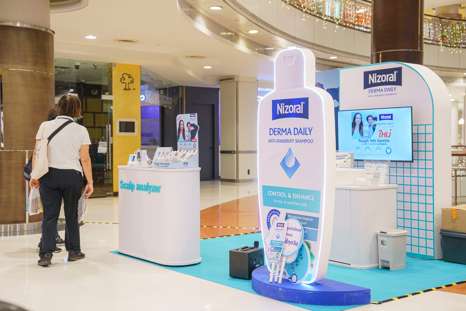 Shopping mall booth promoting Nizoral anti-dandruff shampoo with display stands and promotional materials.