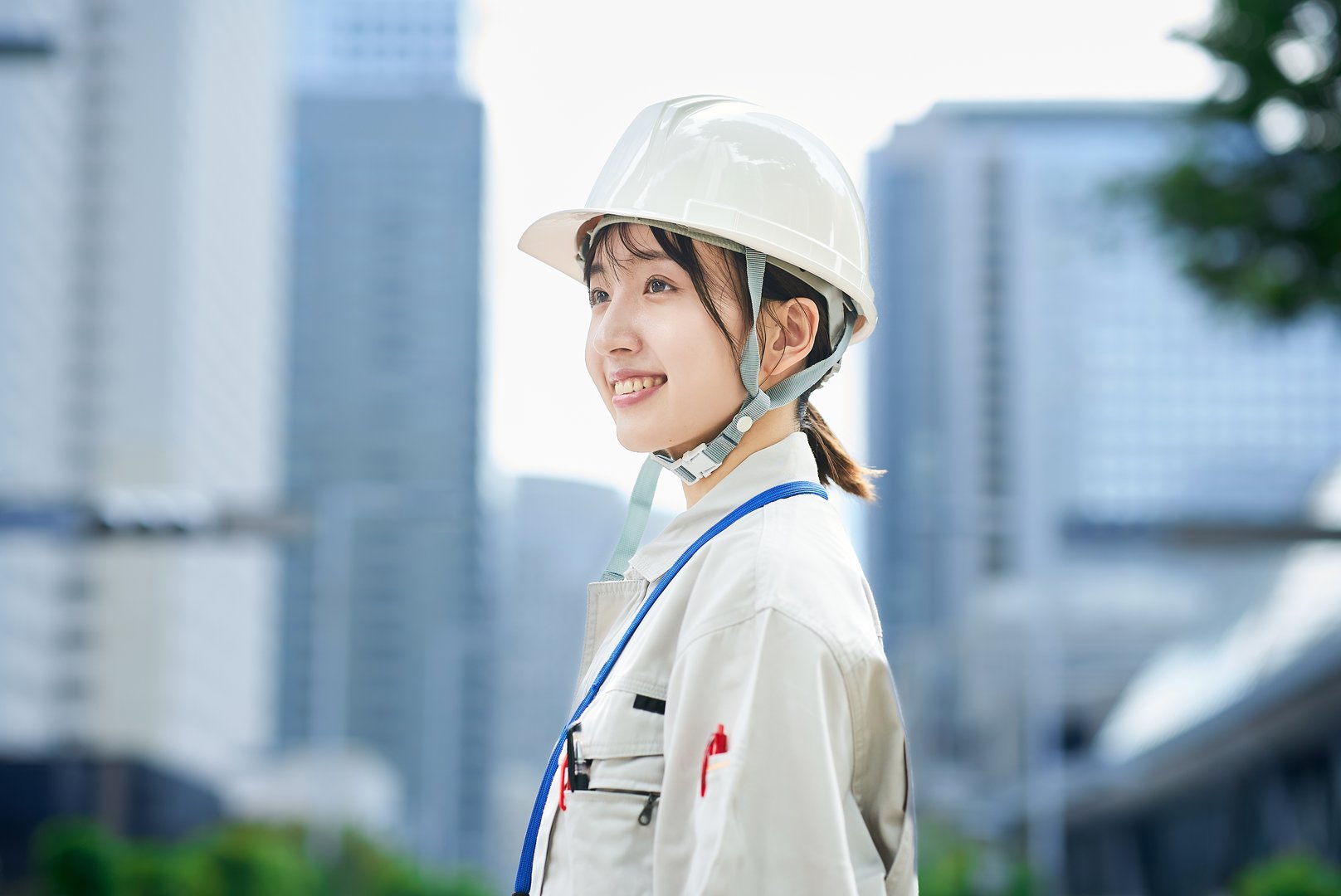 A young woman wearing work clothes and a helmet outdoors