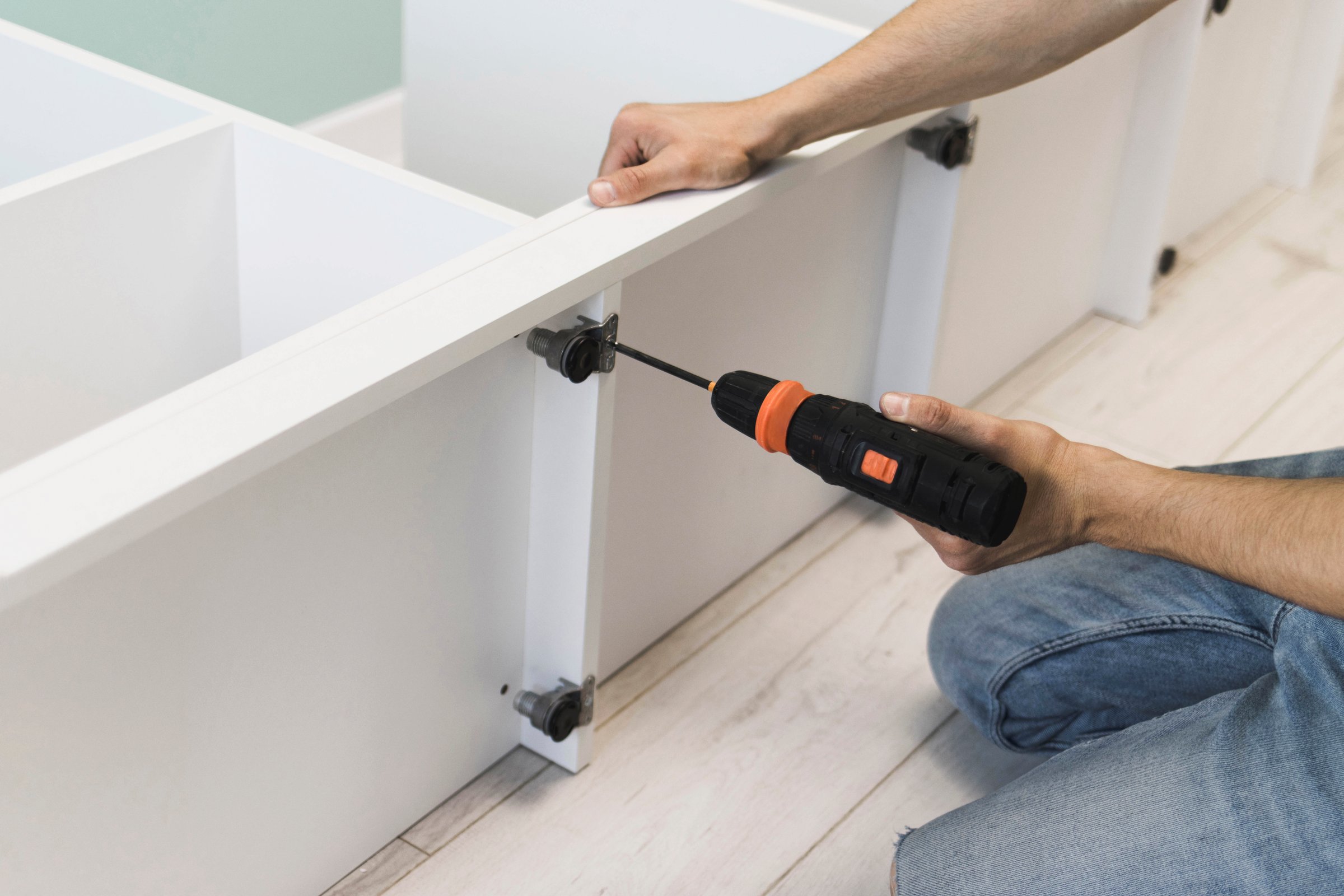 A young craftsman assembles furniture fittings. Screwing the confirmat close-up. Professional furniture assembling. Installation of new furniture. Furniture assembly.