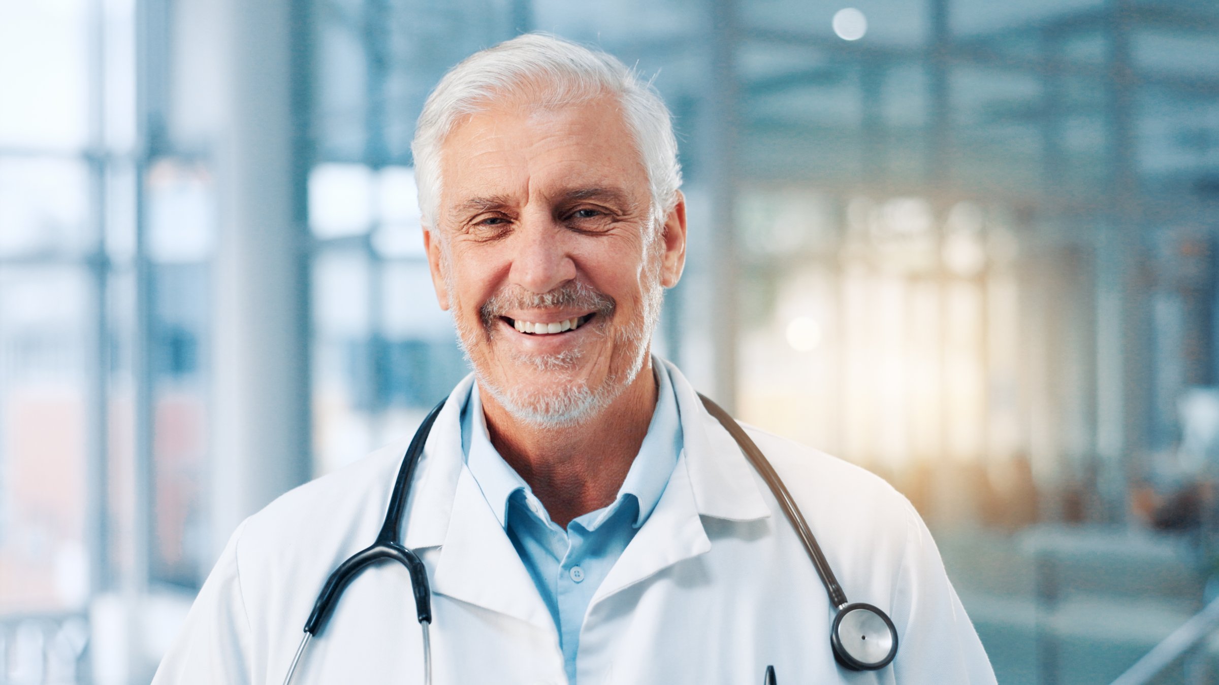 Portrait, mature man and doctor in healthcare with smile, professional career or wellness in clinic. Hospital, male person and cardiologist with confidence for about us, medical employee and happy