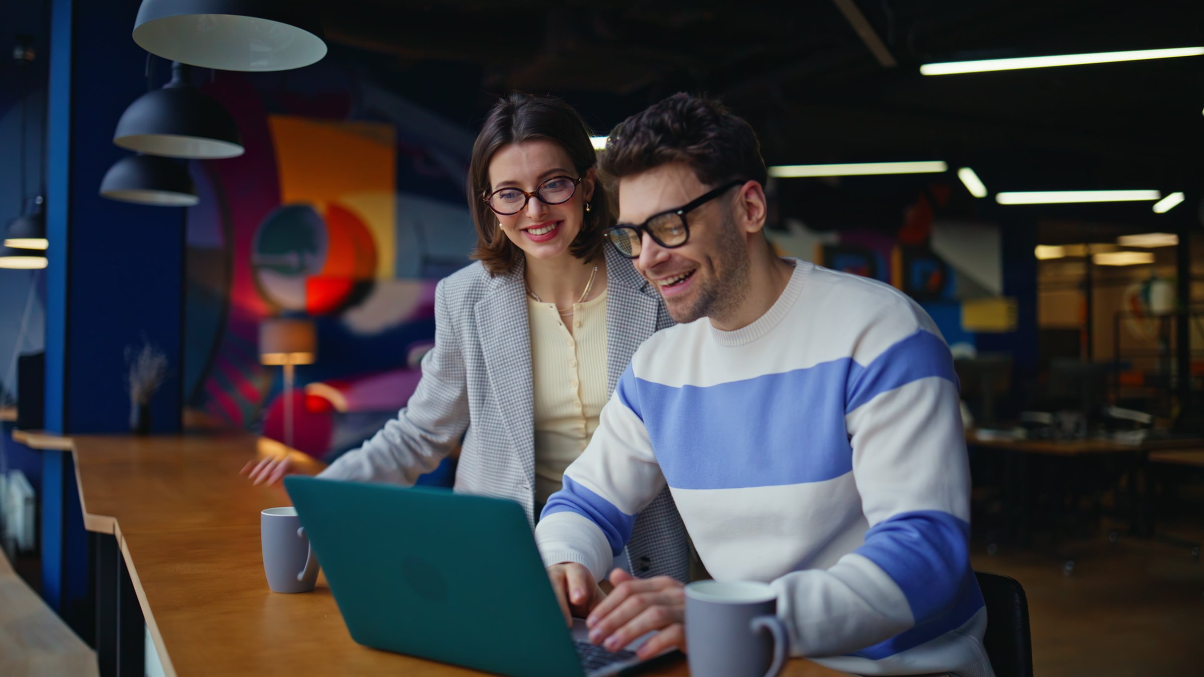 Smiling business colleagues videocalling laptop in modern cafeteria counter closeup. Professional man woman explaining project details to client. Cheerful teamwork talking virtual meeting indoors
