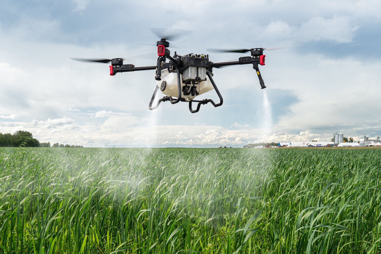 Agriculture drone against the background of blue sky and green fields with agricultural plants. drone for pollination of plants. Modern technologies in agriculture.