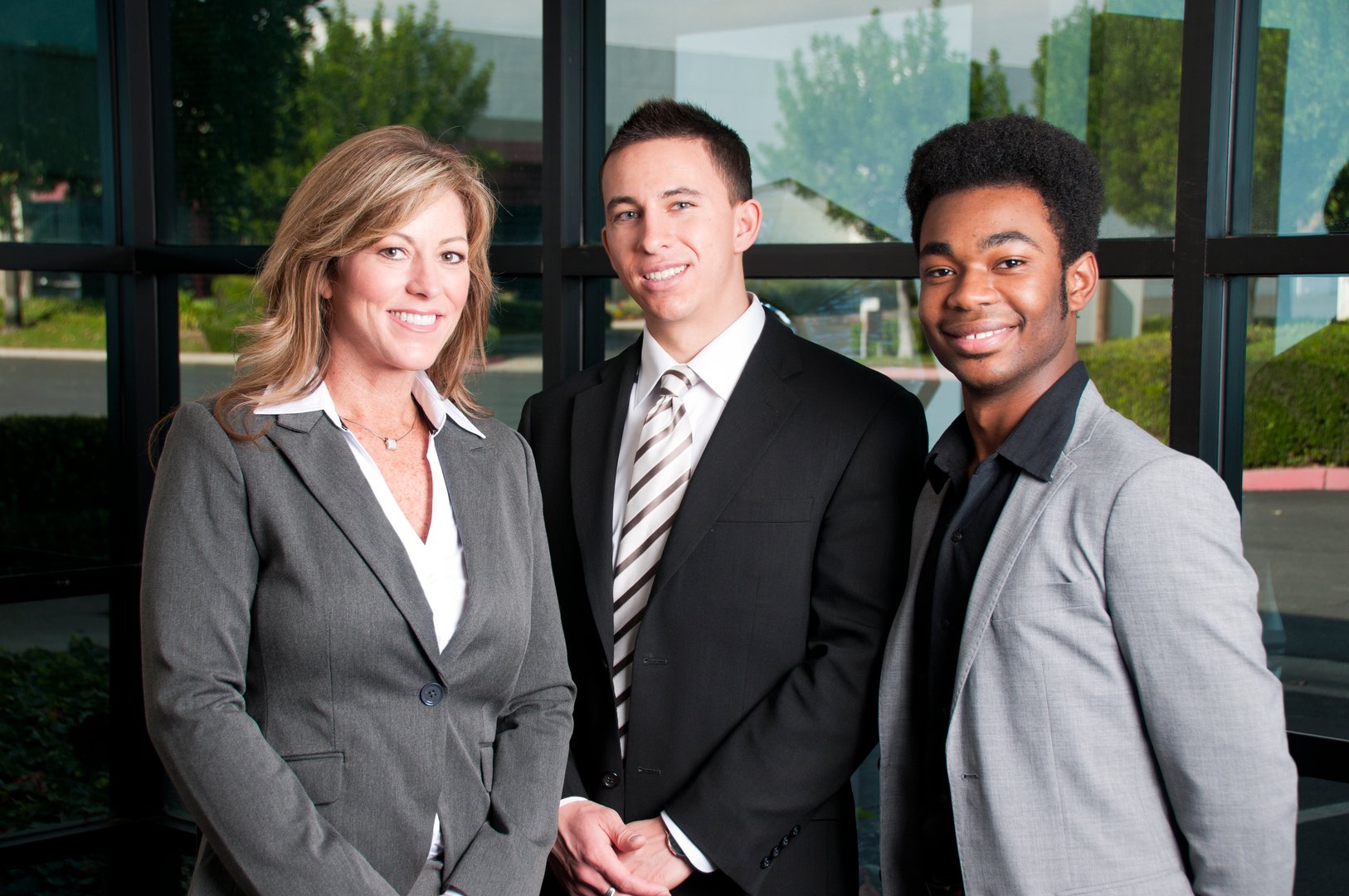 Three members of a business development team stand and smile at the camera.View more image of this model in this lightbox: