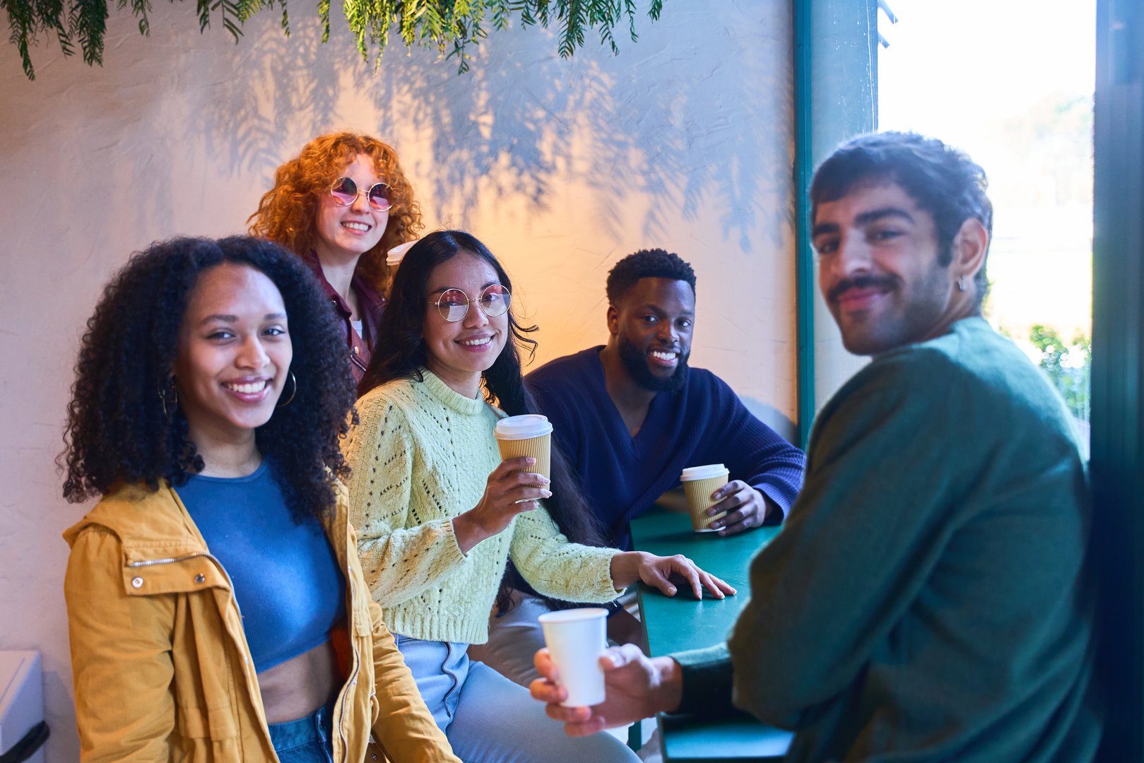 Happy multi ethnic friends spending leisure time together, drinking coffee and chatting in a trendy cafe