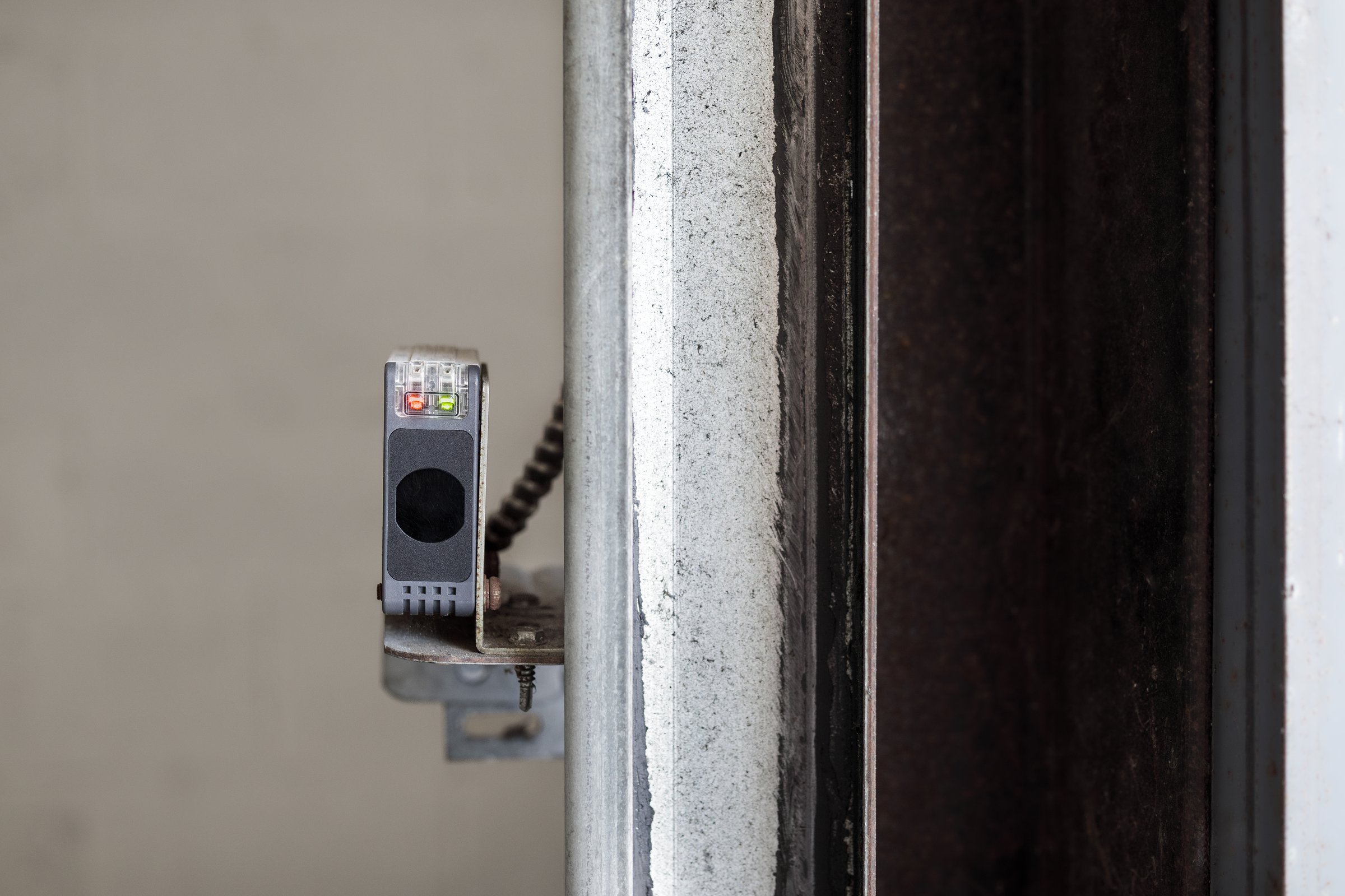 Close up of photoelectric sensor with connected to overhead sectional door in parkade. Safety equipment for detection and prevention of accidents. Selective focus.