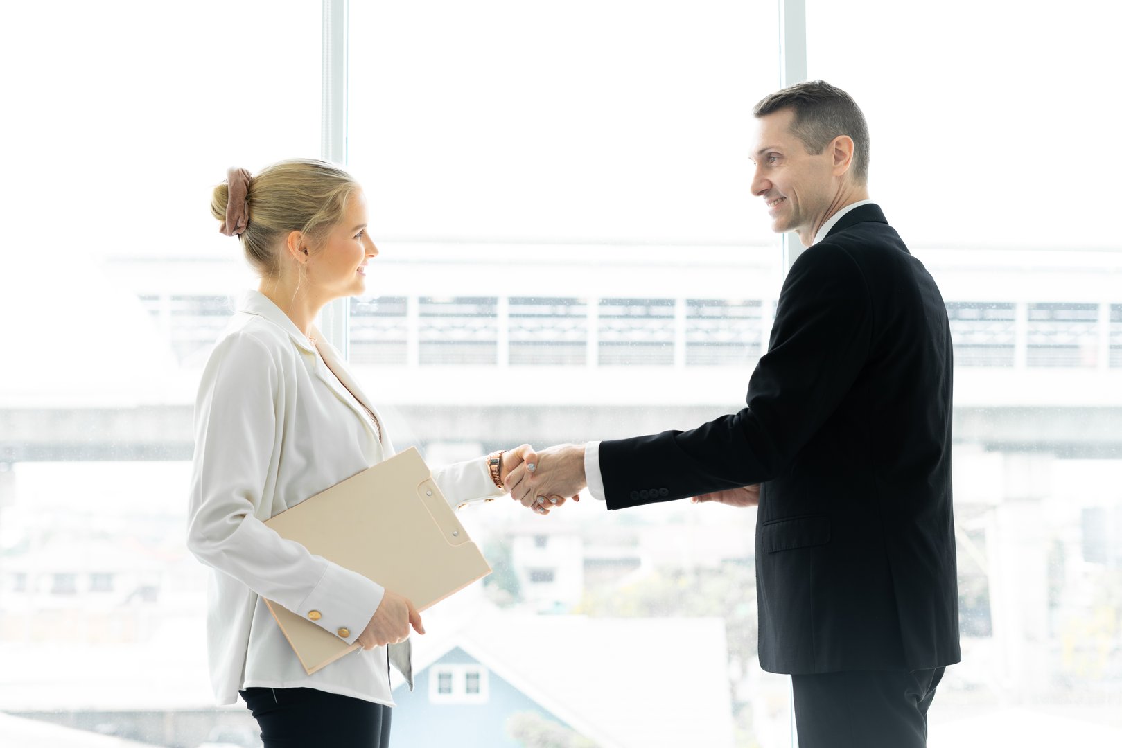 business man and woman shaking hands at meeting room in office with window