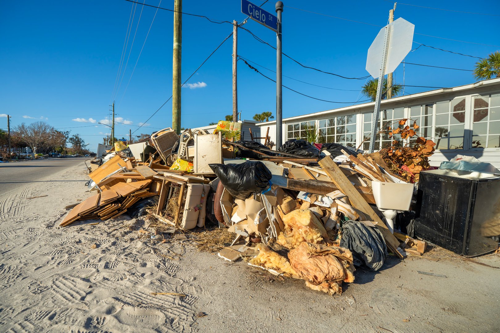 Consequences of natural disaster. Trash from severely damaged houses after hurricane storm surge. Piles of debris on street side in Florida.