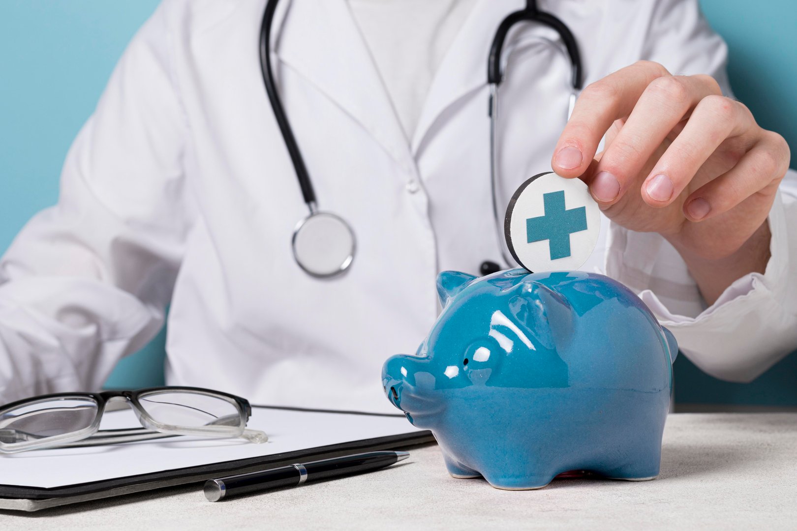 Person in white coat putting coin with medical cross into blue piggy bank, representing healthcare savings.