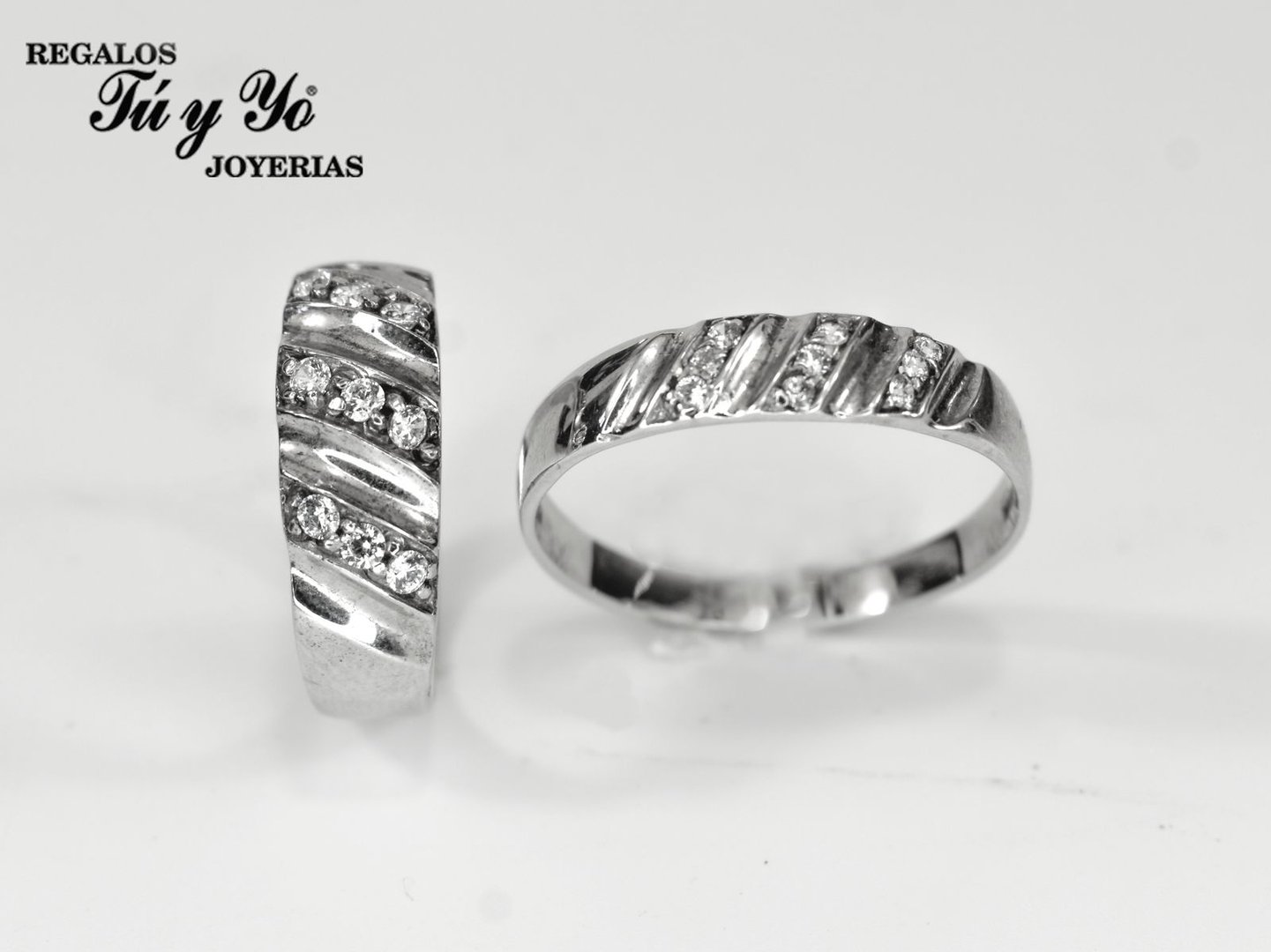 Two silver rings with diagonal grooves and embedded diamonds, set against a plain background.