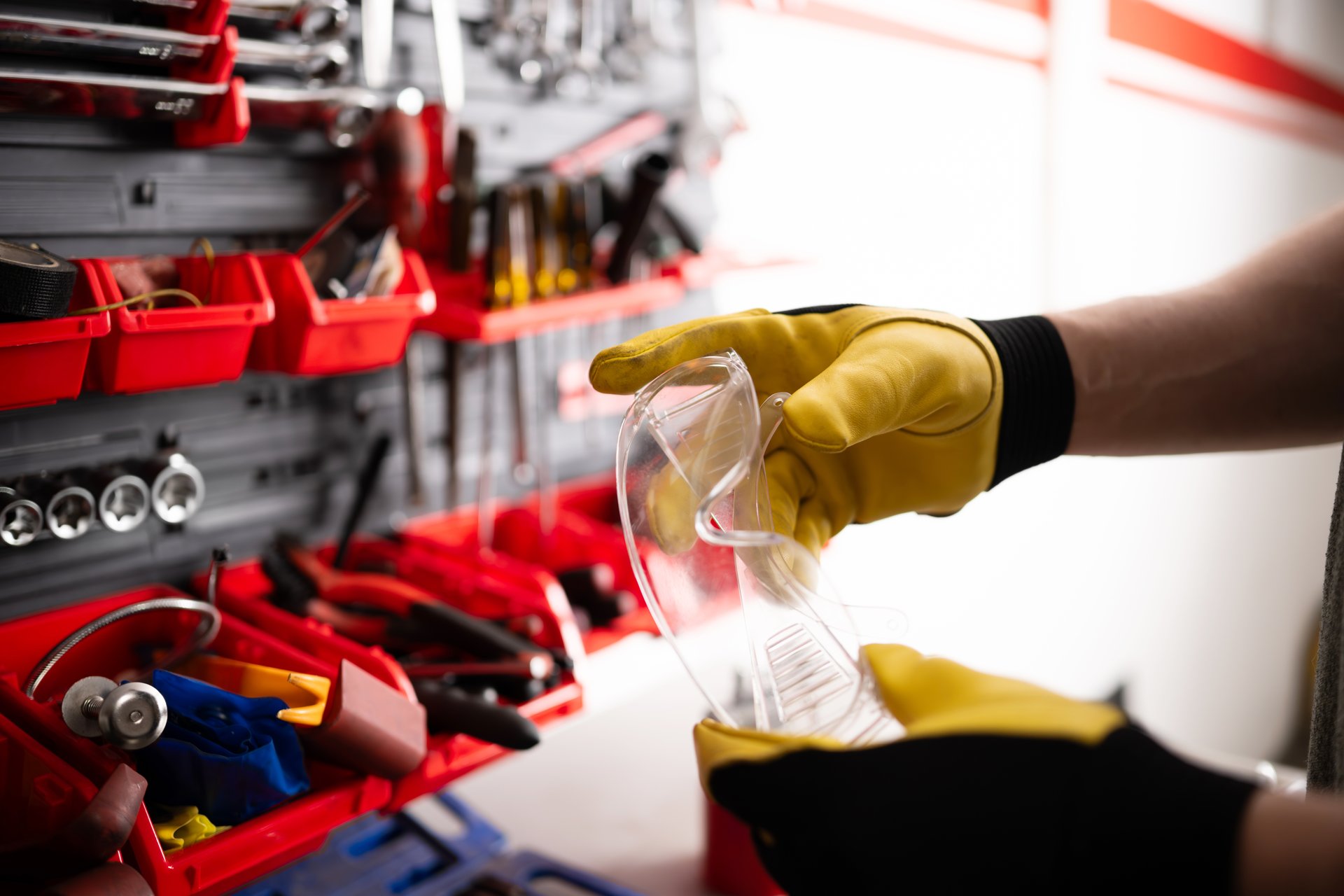 Mechanic Holds Protective Goggles In Hand At The Garage Workspace