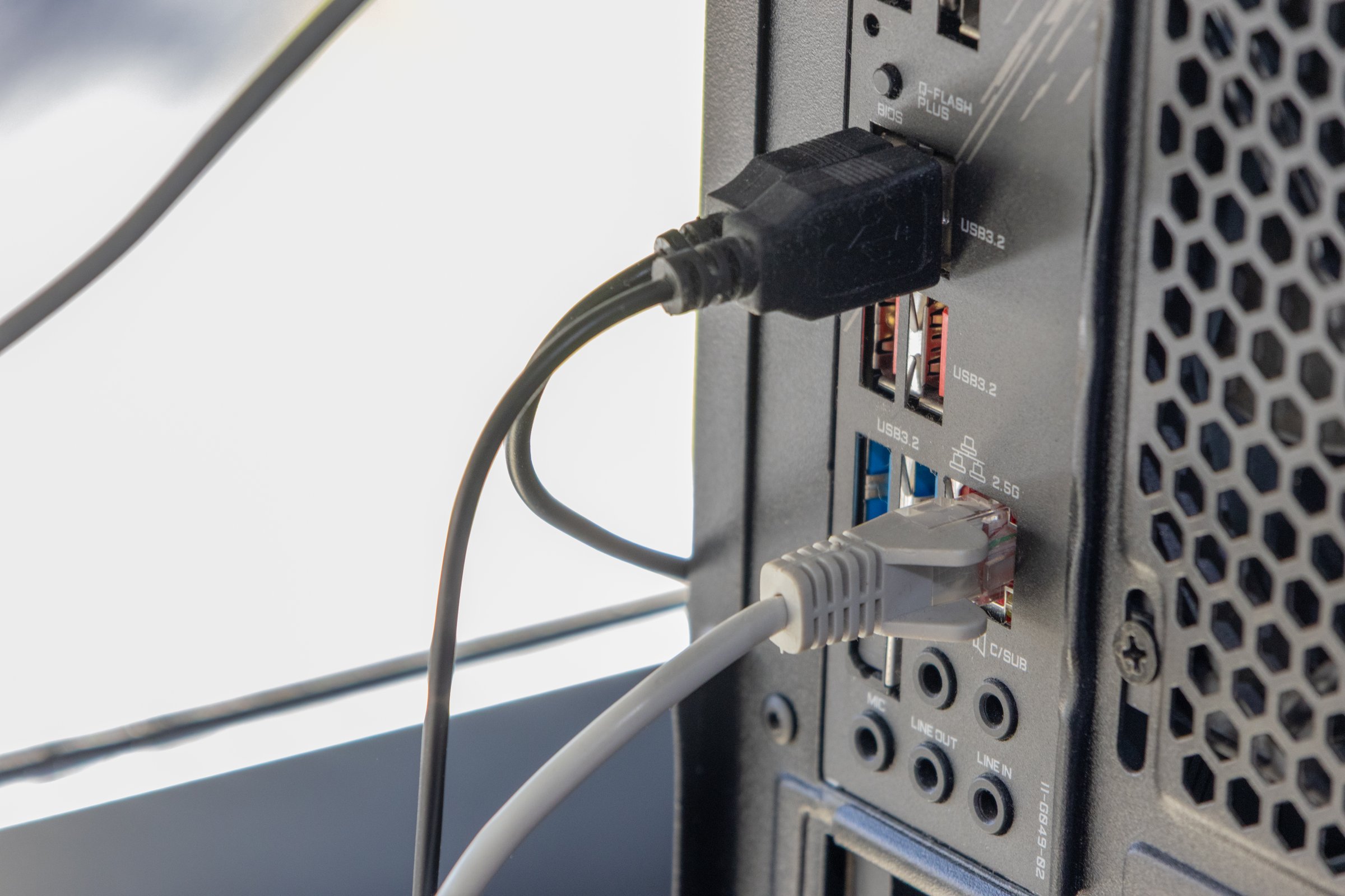 Usb and ethernet cables plugged into ports on the back of a computer, enabling data transfer and network connectivity