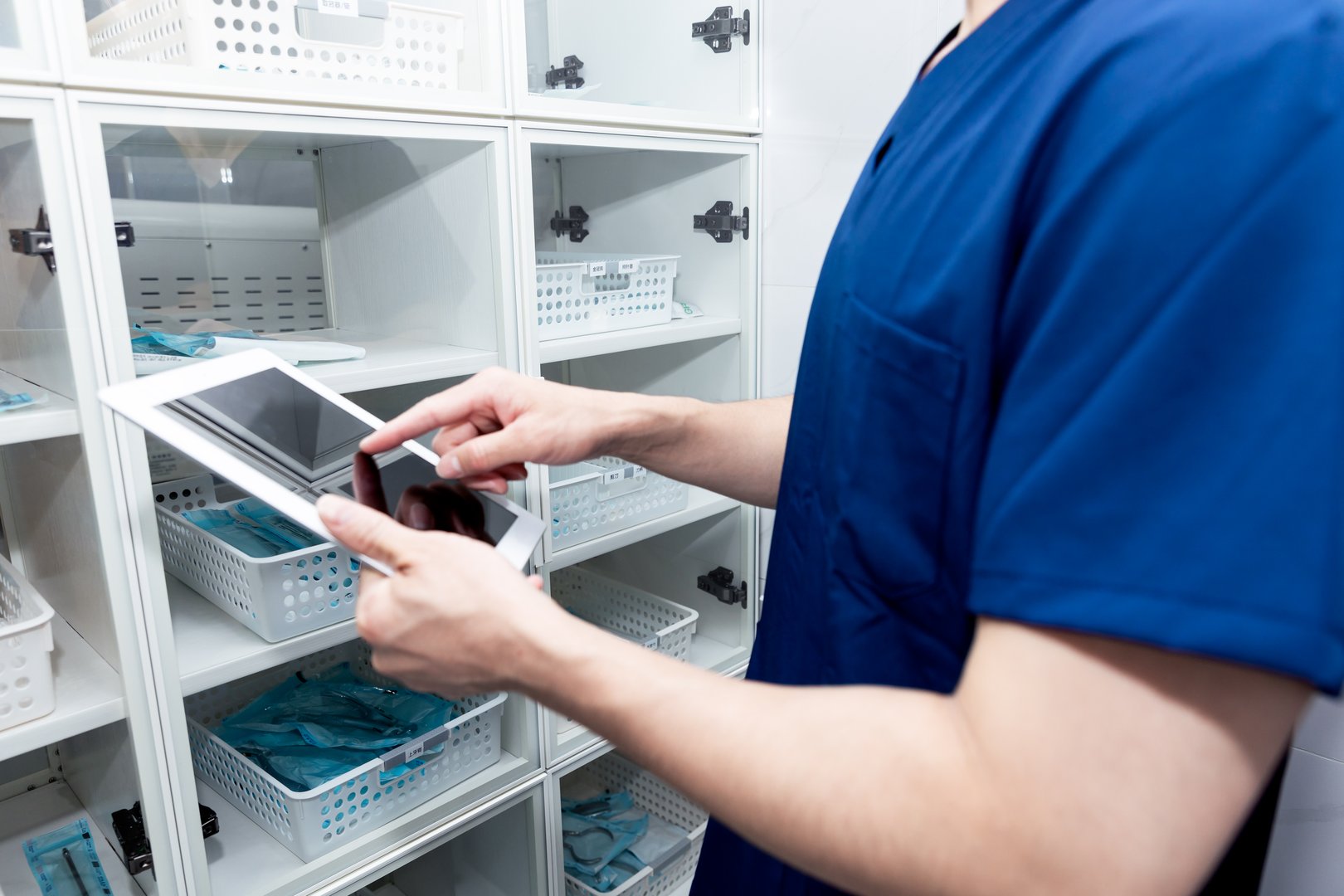 Male nurse searching something in operation room cabinet. men healthcare professional wearing medical scrubs and surgical cap looking cabinet in surgery room.