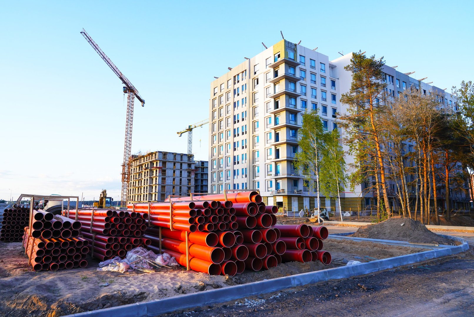 Drainage and sewer pipes for waste water, drains, sewers. Tower Crane on building construction. Construction crane on Construction site. Residential Buildings construction. Building renovation.