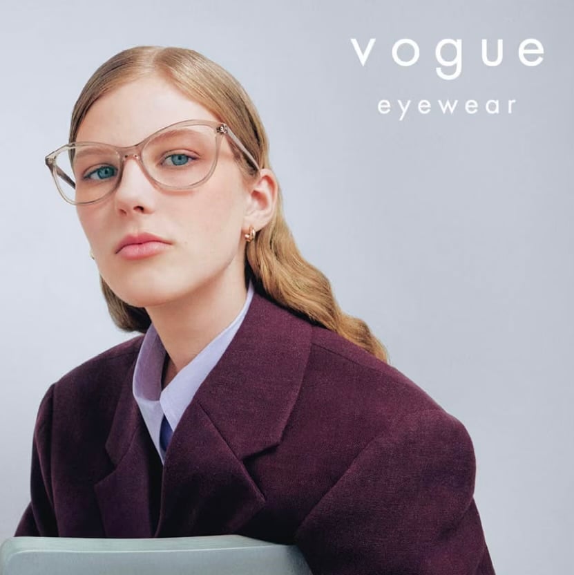 Person wearing stylish glasses and a purple blazer, posing in front of a white background. "Vogue Eyewear" text displayed.