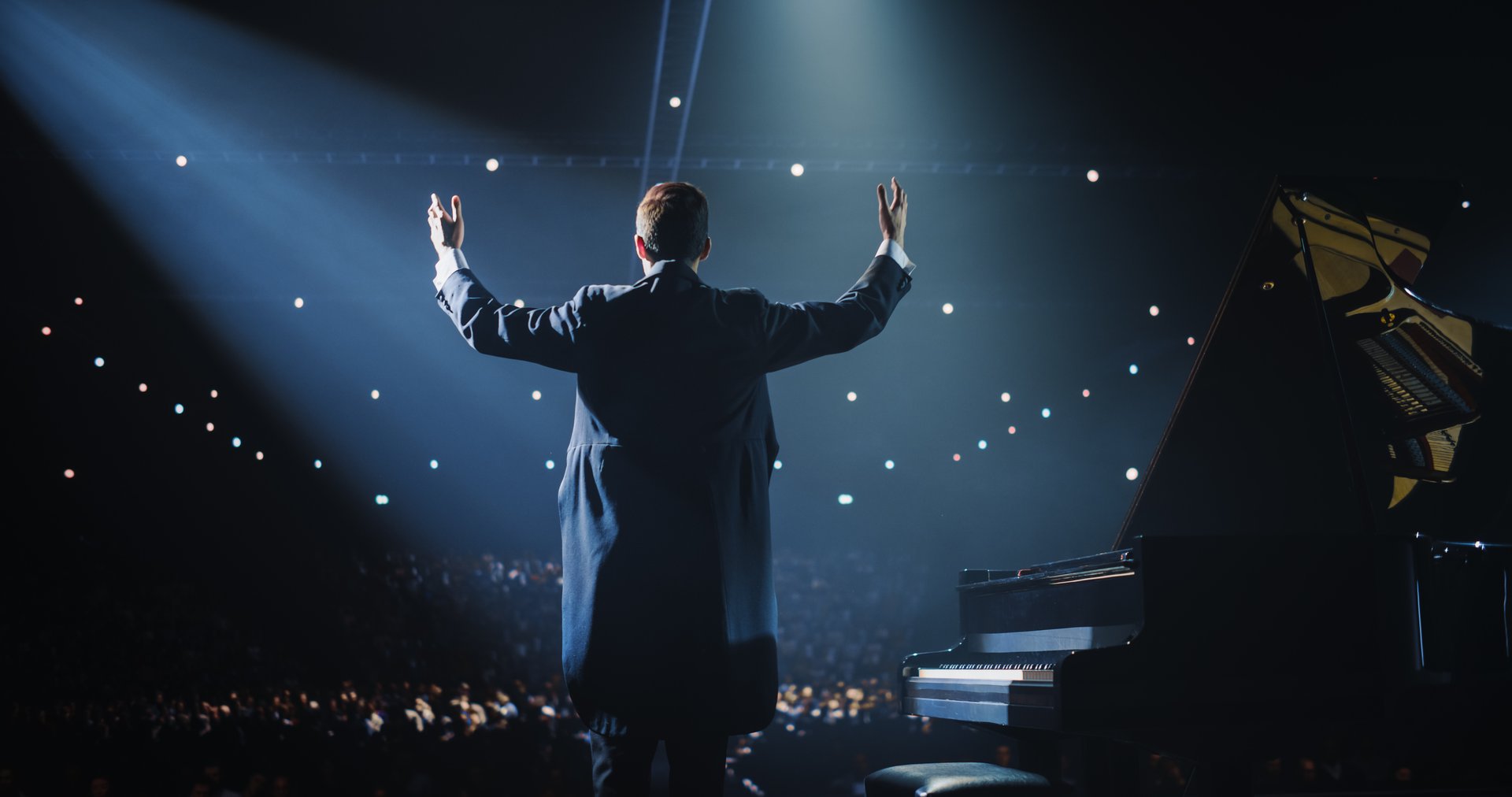 Pianist, Standing Proudly on Stage, Takes a Moment to Thank the Audience. He is Looking Straight at the Crowd, Showing Respect. He Thanks the Spectators for Their Overwhelming Support