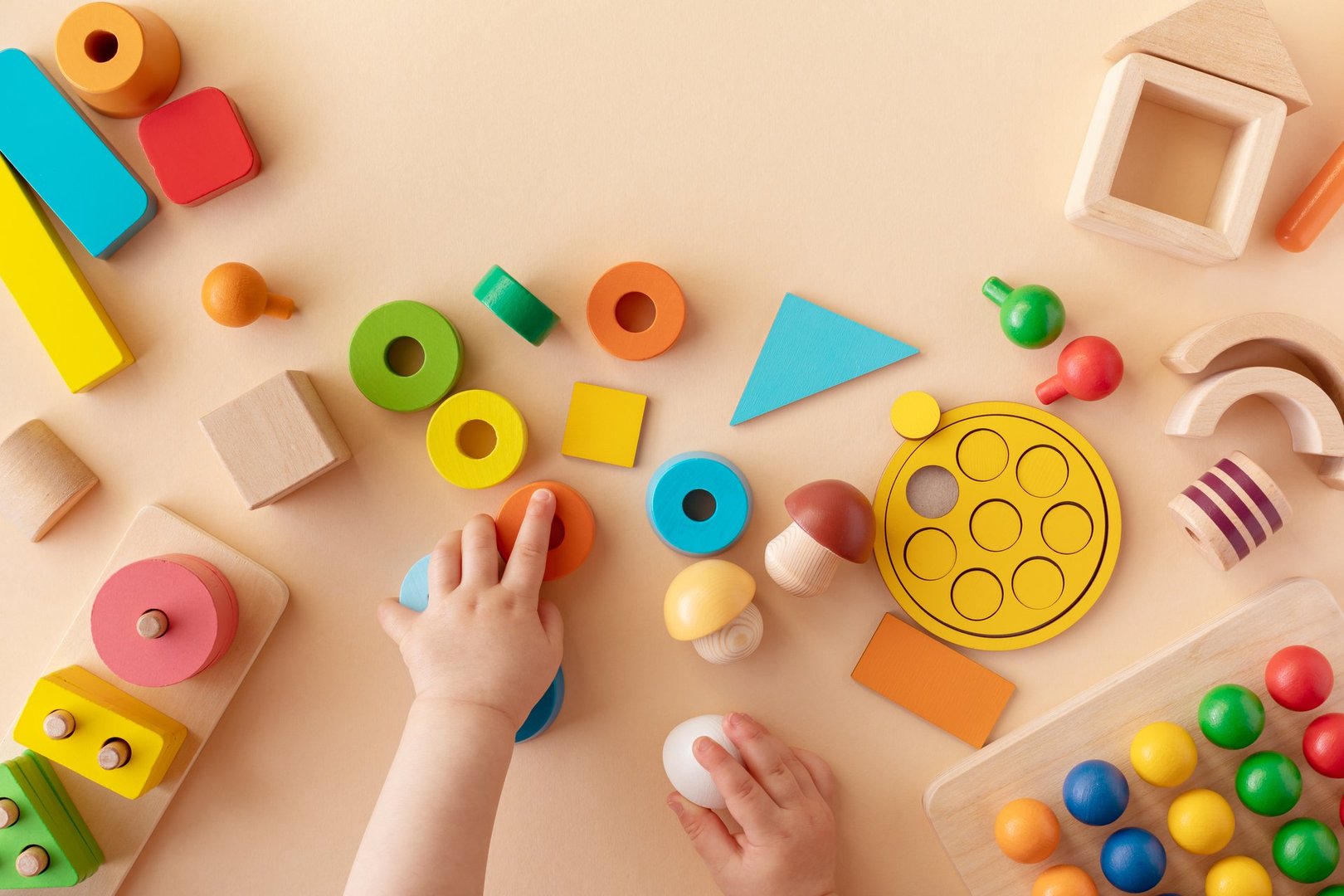 Manos de bebé jugando con juguetes educativos coloridos de madera para desarrollo sensorial
