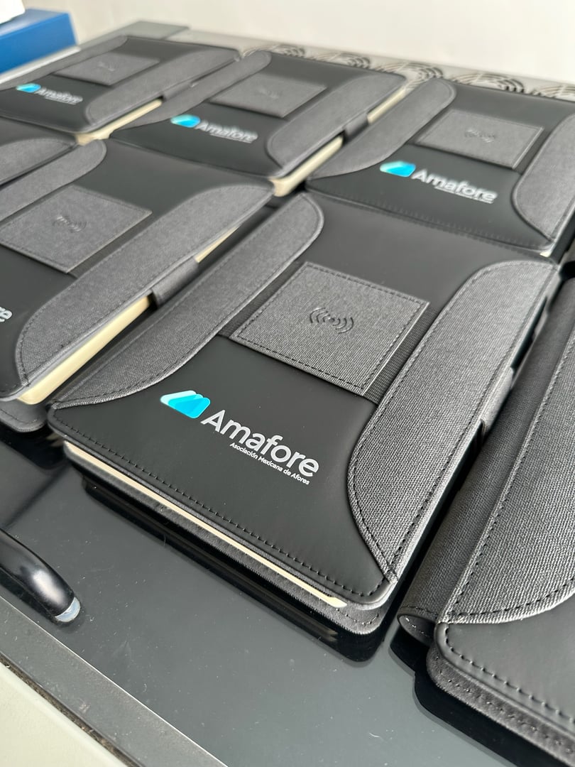 Black notebooks with "Amafore" logo and wireless charging pads, neatly arranged on a table.