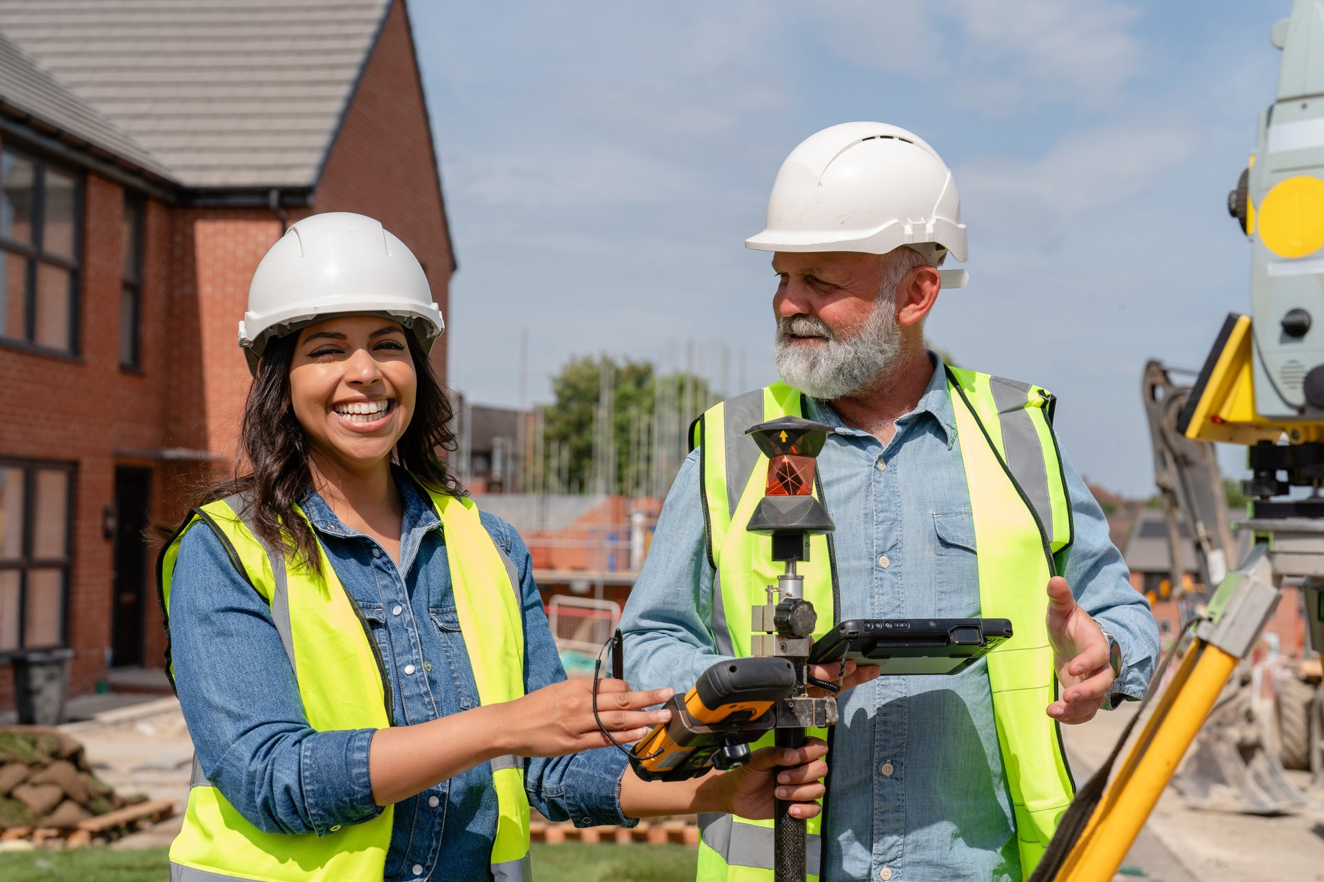 Male construction works project manager and young female site engineer collaborating on-site, discussing project details and future plans at building site