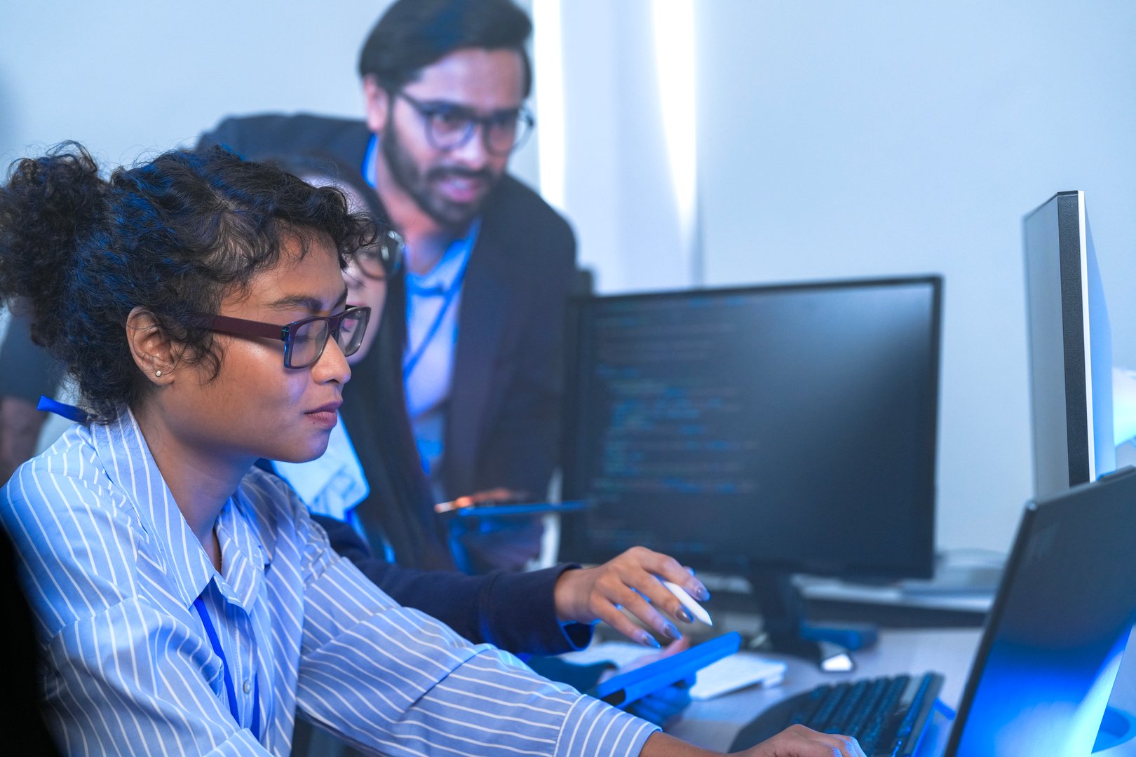 A senior tech lead or manager mentoring a diverse team of junior developers in a modern office