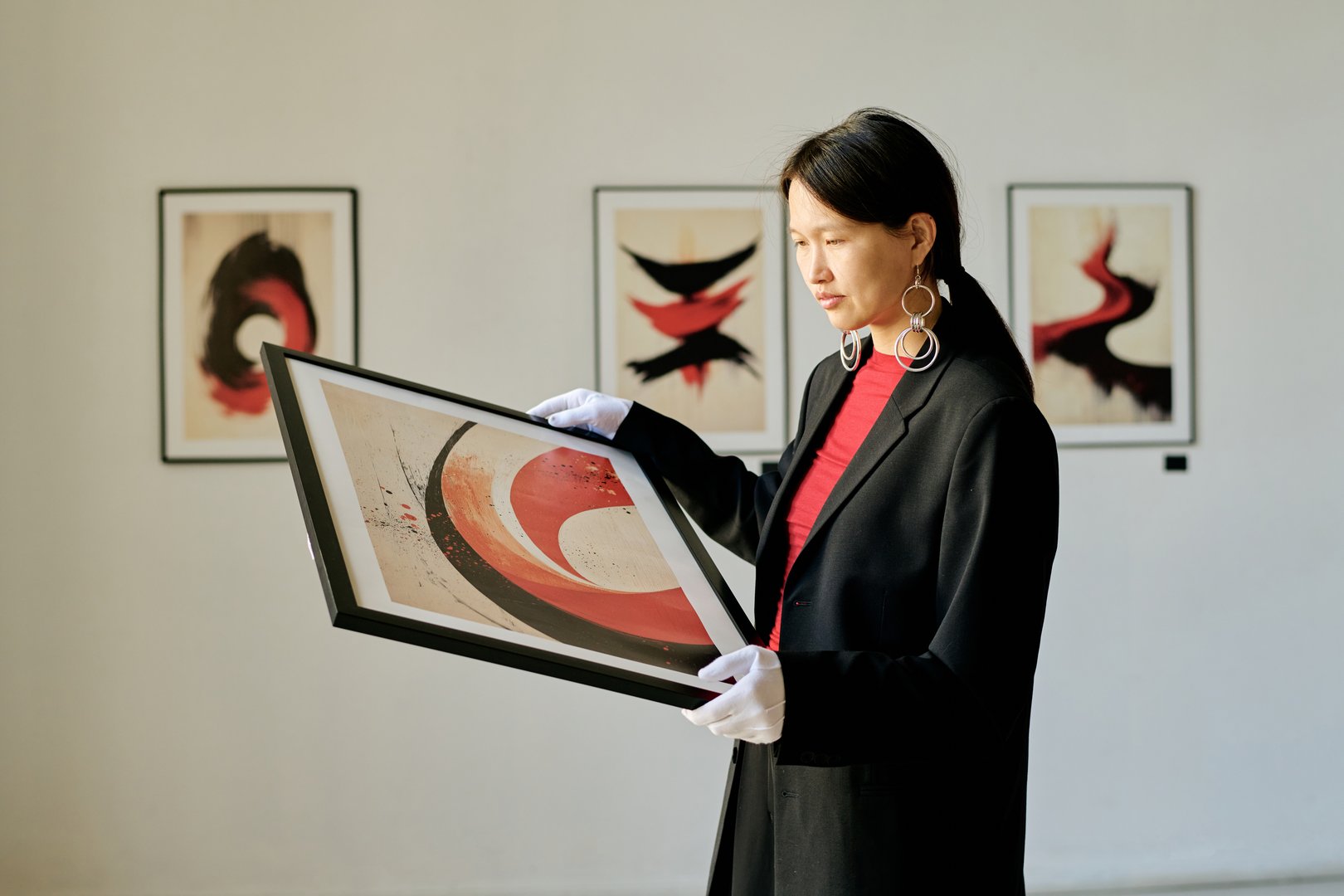 Woman in a gallery admiring abstract art print, holding framed artwork and contemplating creativity, surrounded by other art pieces in a sophisticated setting