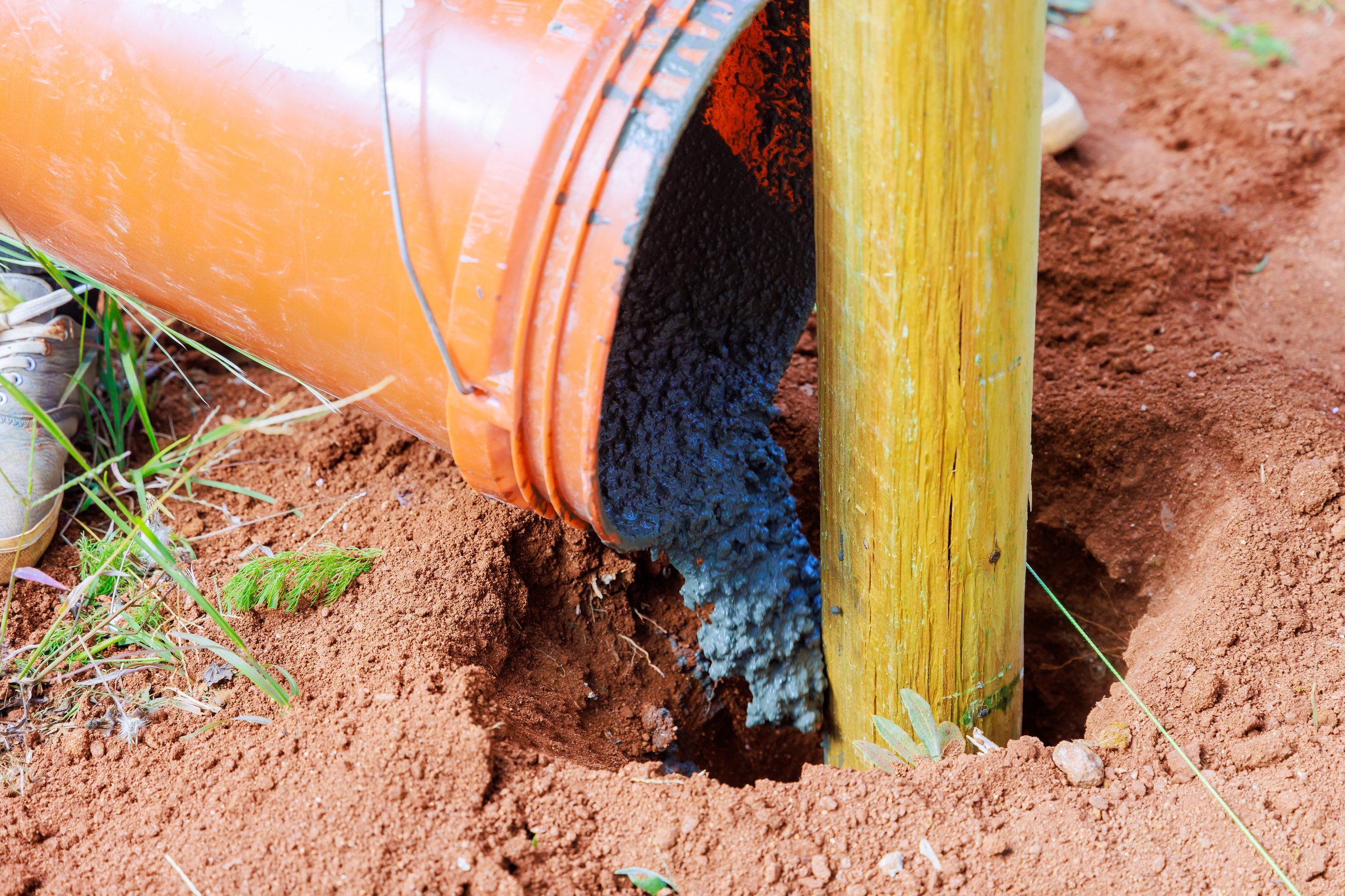 Pouring concrete on newly installed timber fencing wooden fence posts