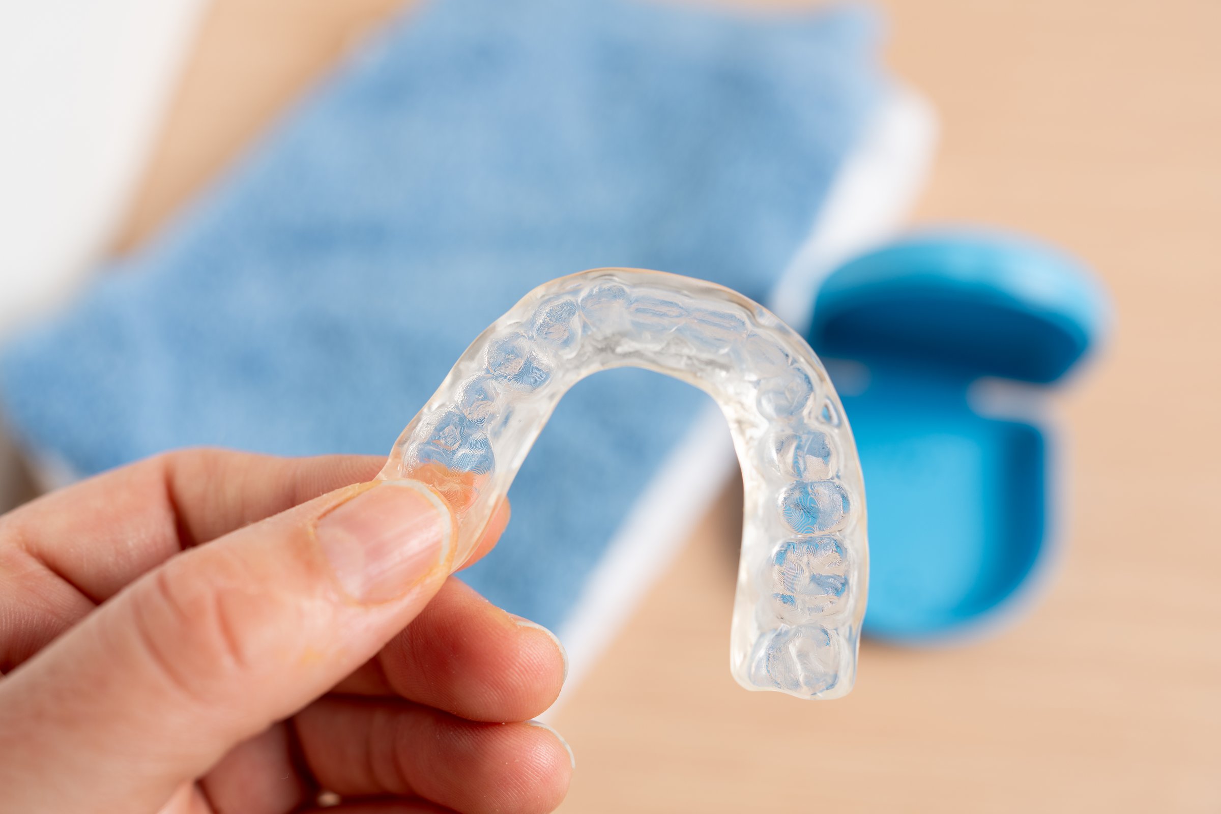 Woman hand with holding a silicone trainer in a bathroom with a blue box in the background