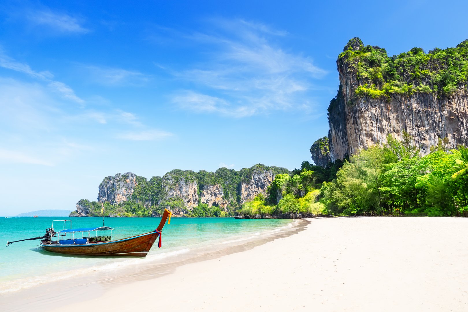 Thai traditional wooden longtail boat and beautiful white sand Railay Beach in Krabi province, Ao Nang, Thailand. Amazing view of beautiful beach with long tail boat in Railay beach, Krabi, Thailand.