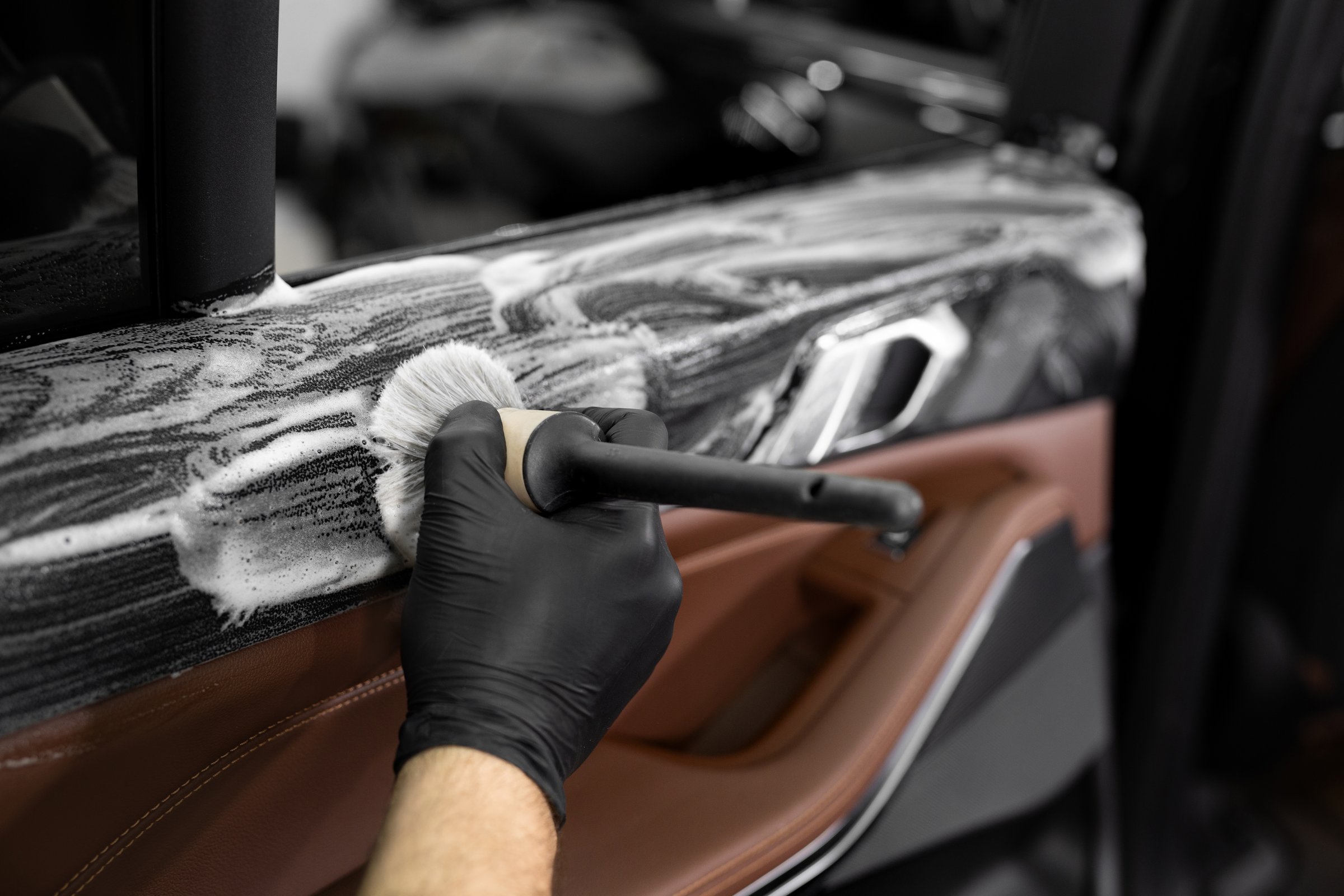 Washing with foam and detergent using a brush on the inner surface of the car door. Car detailing service.