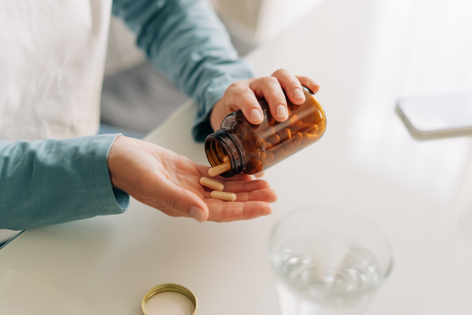 Close-up of an unrecognizable woman's hands holding a jar of capsules