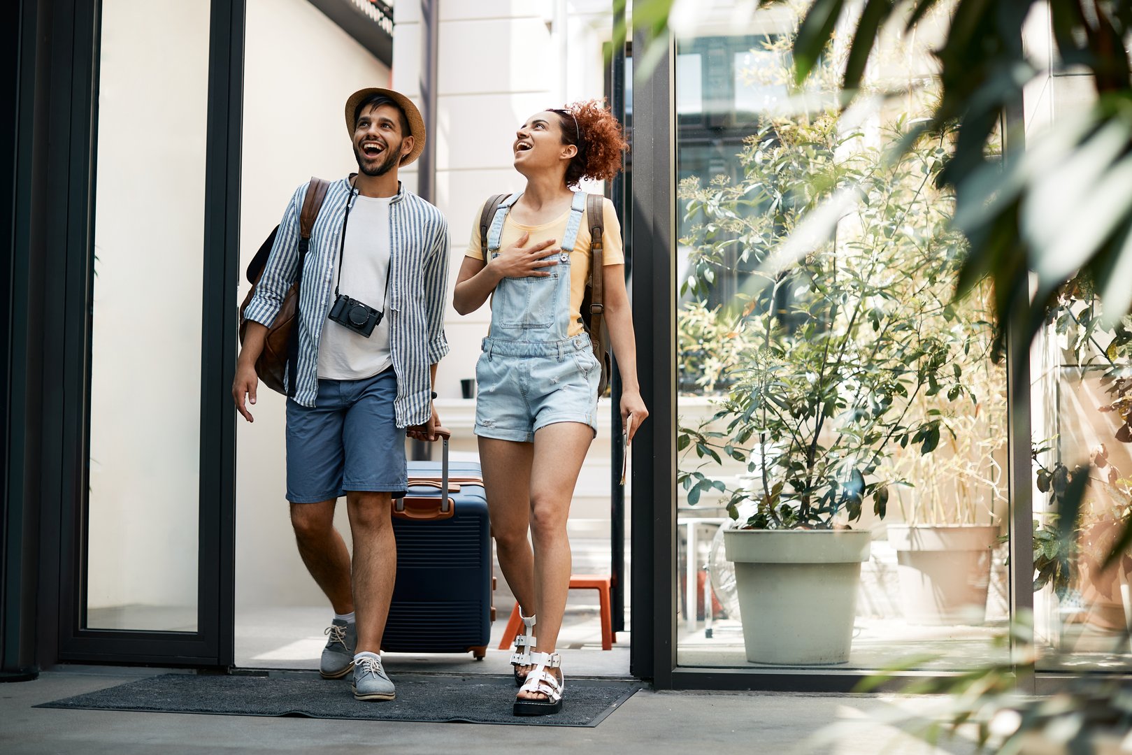 Full length of excited tourist couple entering in a hotel.