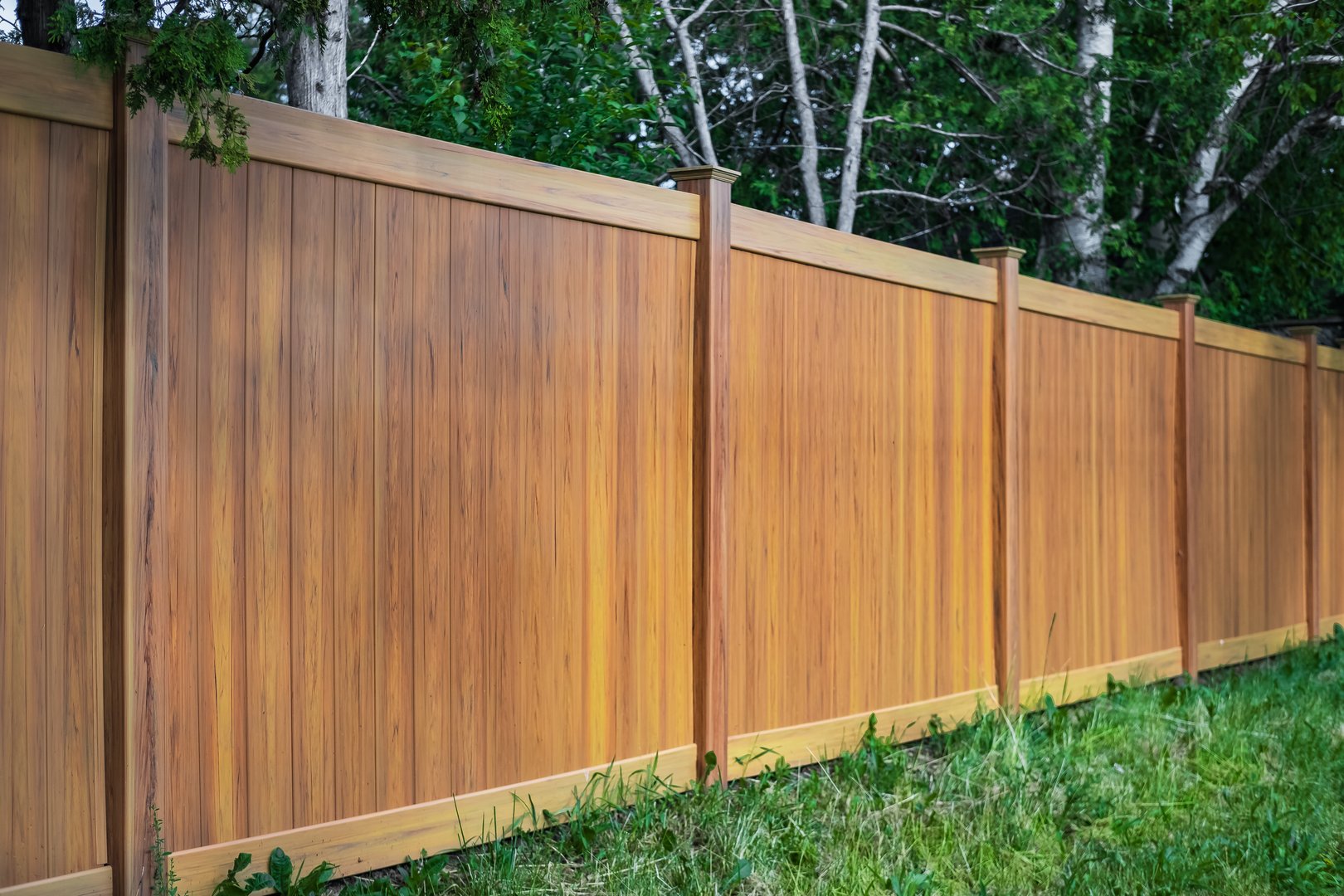 Nice new wooden fence around house. Wooden fence with green lawn. Street photo, nobody, selective focus