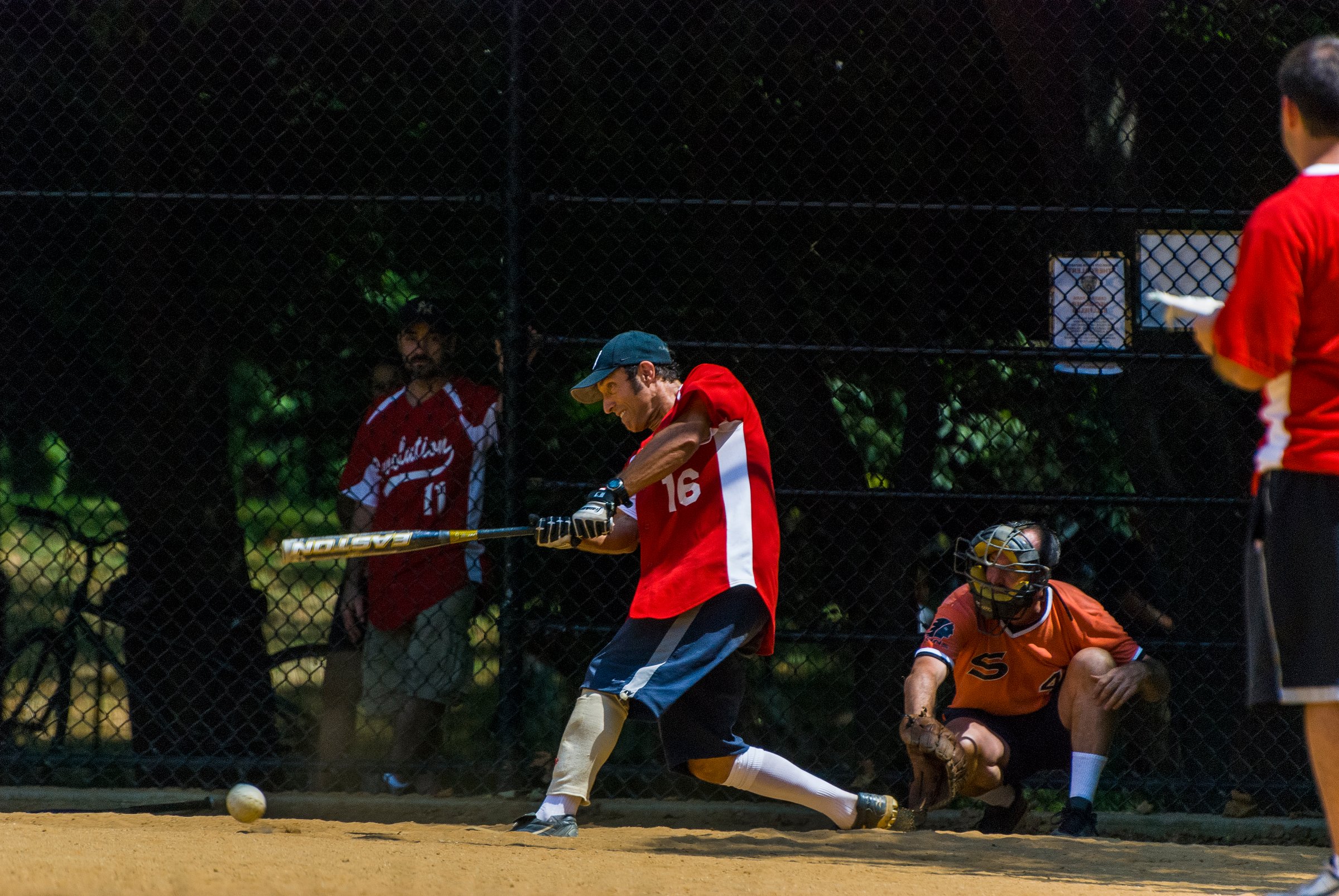 People playing softball on a field in central park with the batter swinging his bat to hit the ball. New York, NY, United States, July 12, 2010.