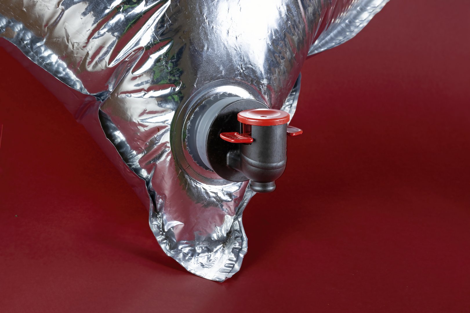 Wine Bag with Spout on Metallic Pouch Against Red Background