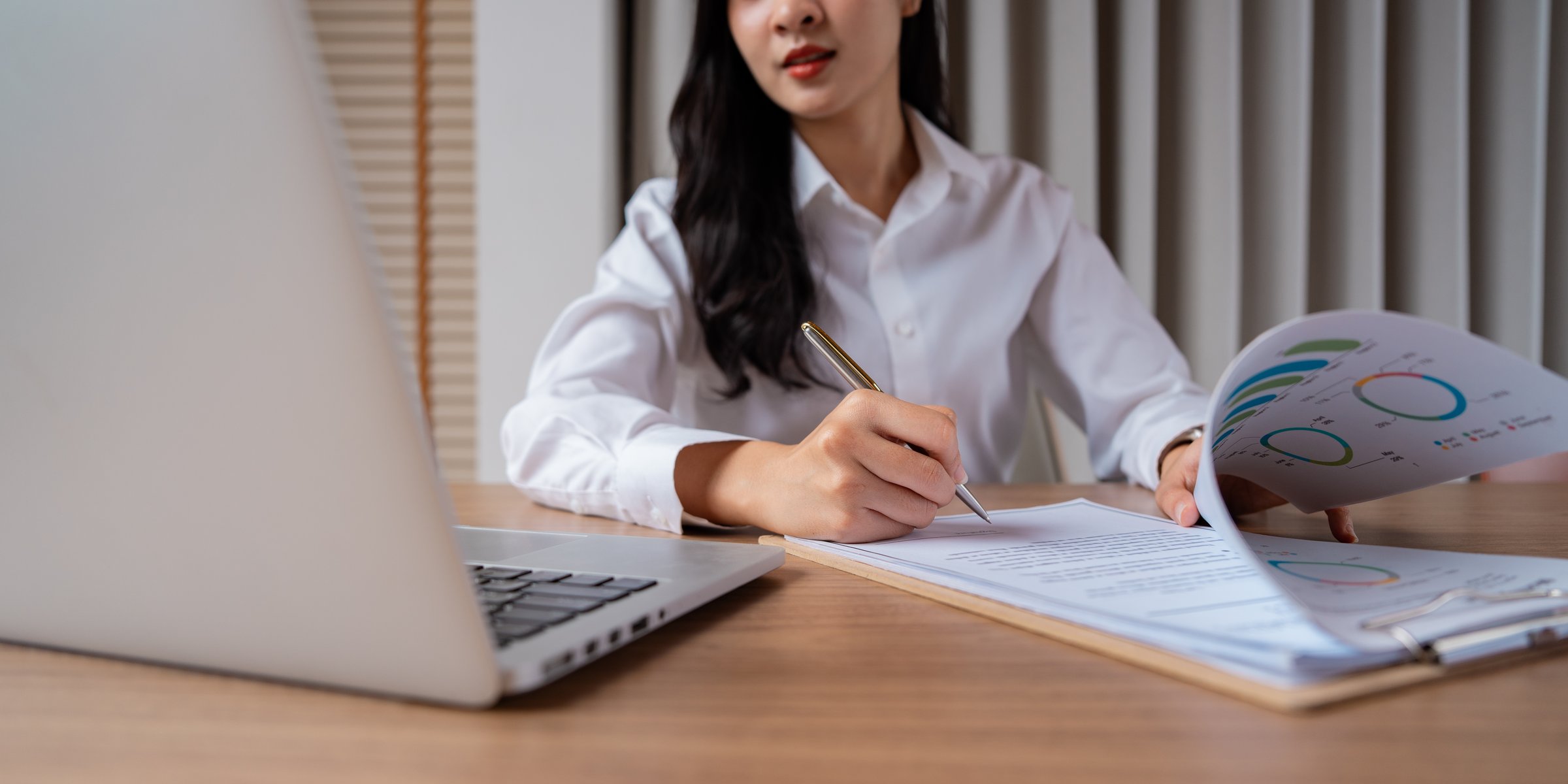 A professional woman engaged in business strategy development, analyzing financial reports and documents to drive informed decisions and enhance performance.