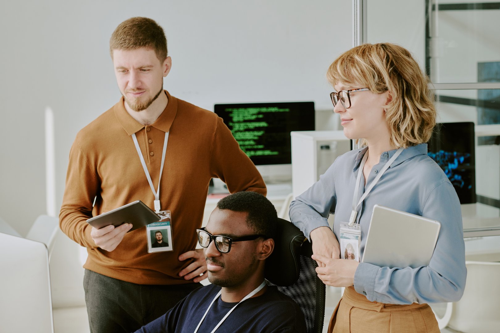 Young Black and Caucasian male and female cybersecurity specialist checking data on computer screen in modern office