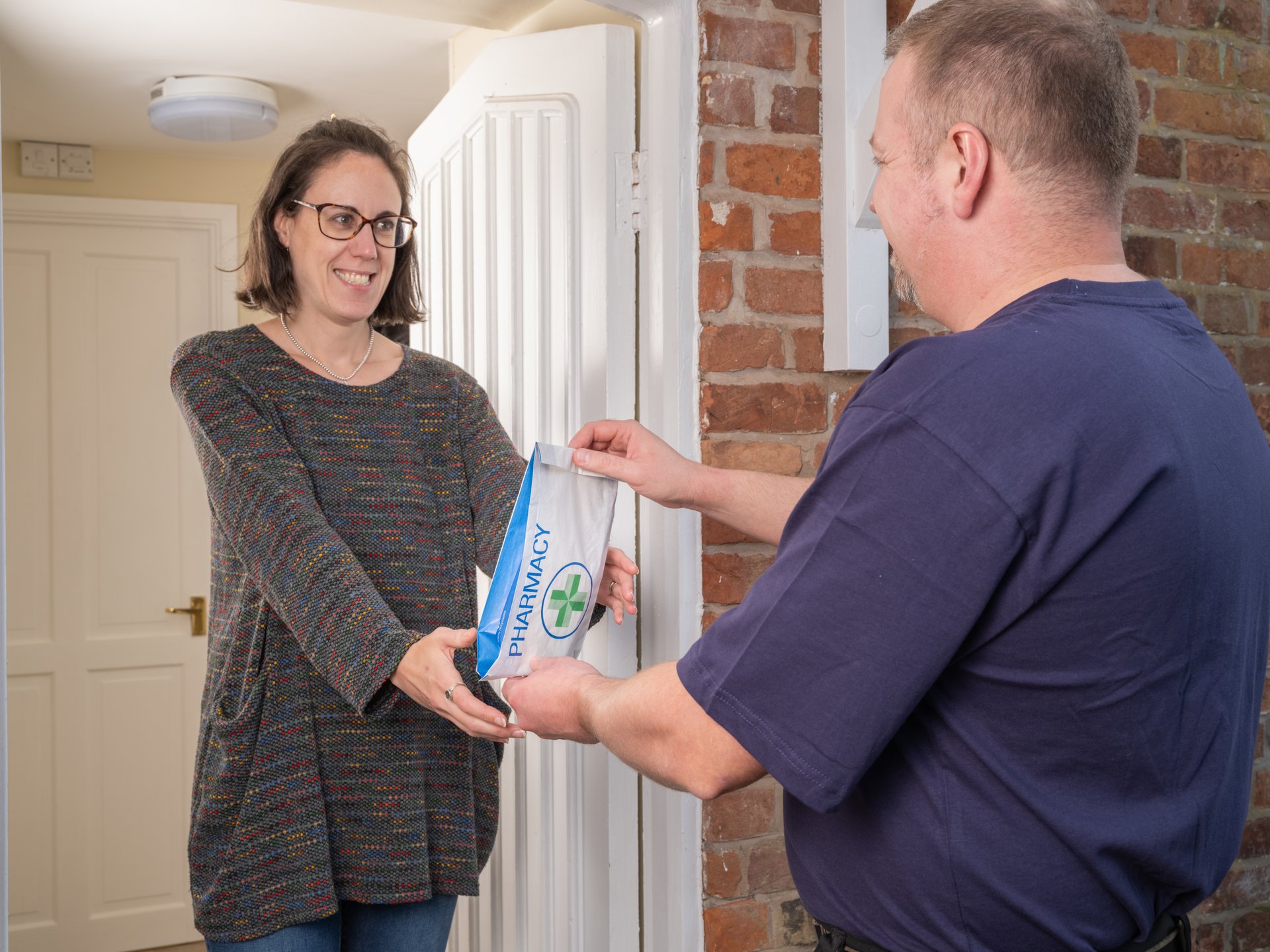 Professional delivery person providing secure prescription medication delivery to a patient at their home