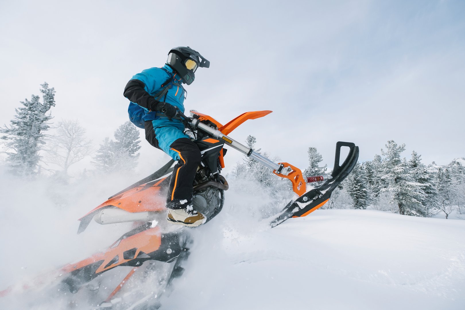 Jumping Snowbike rider in mountain valley in beautiful snow powder. Modify motorcycle with single ski in the front and special snowmobile-style track in the back instead of wheels
