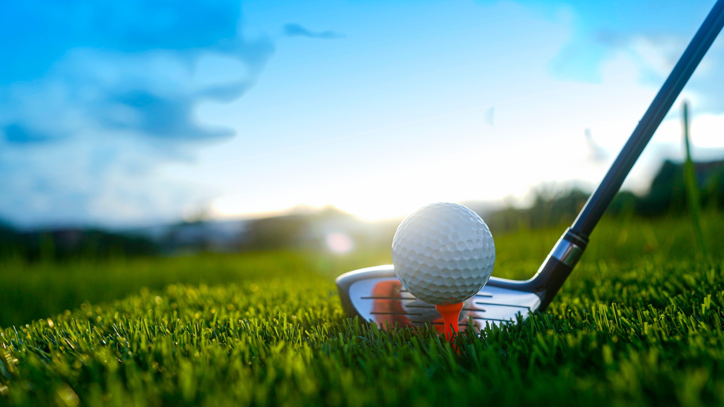 Golf clubs and balls on a green lawn in a beautiful golf course with morning sunshine. Close up of golf equipment on green grass.