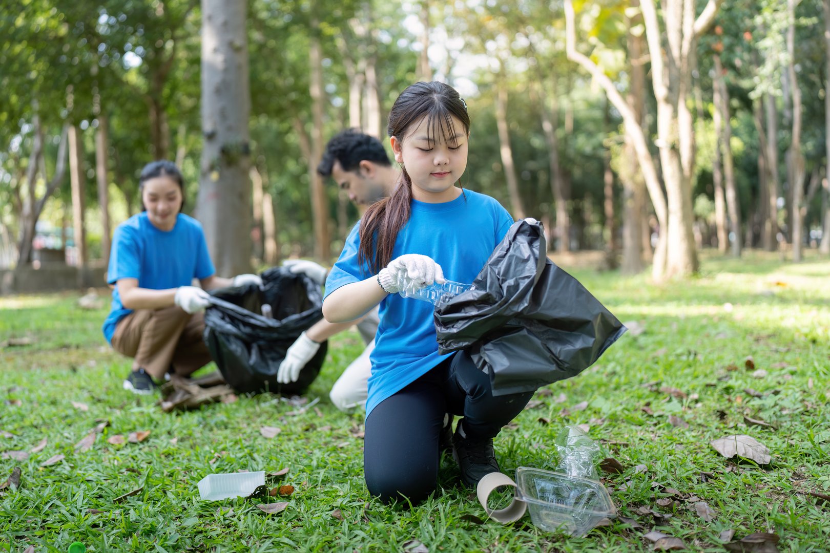 A family volunteering in a park, picking up litter and promoting environmental care. Parents and children working together outdoors.
