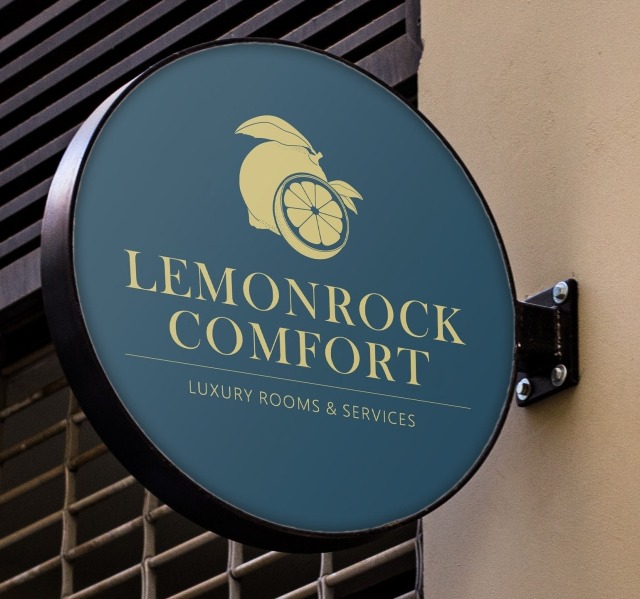 Round sign for 'Lemonrock Comfort' featuring a lemon and text 'Luxury Rooms & Services' on a blue background.