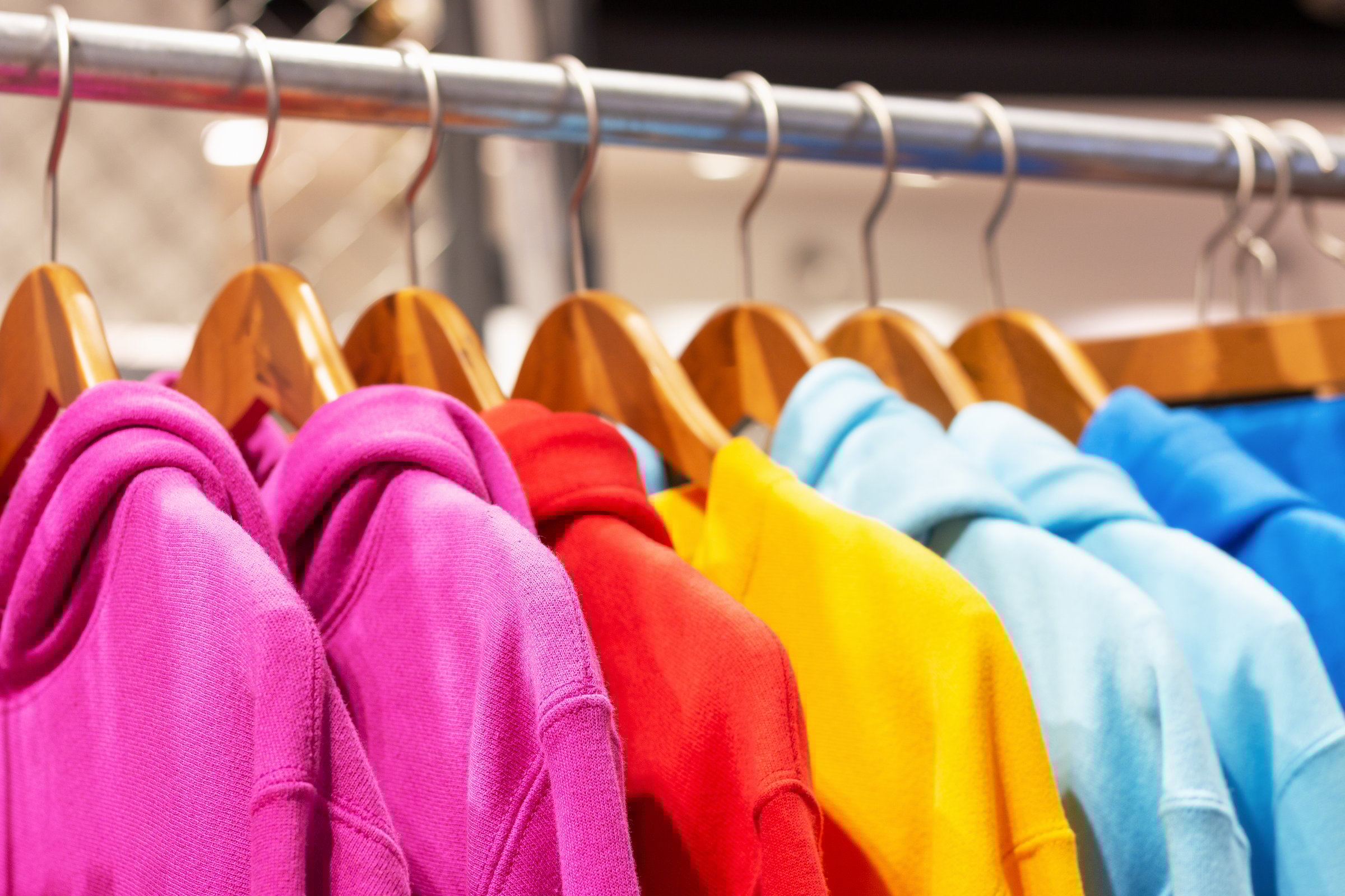 Multicolored hoodies on hangers in a sports store close up